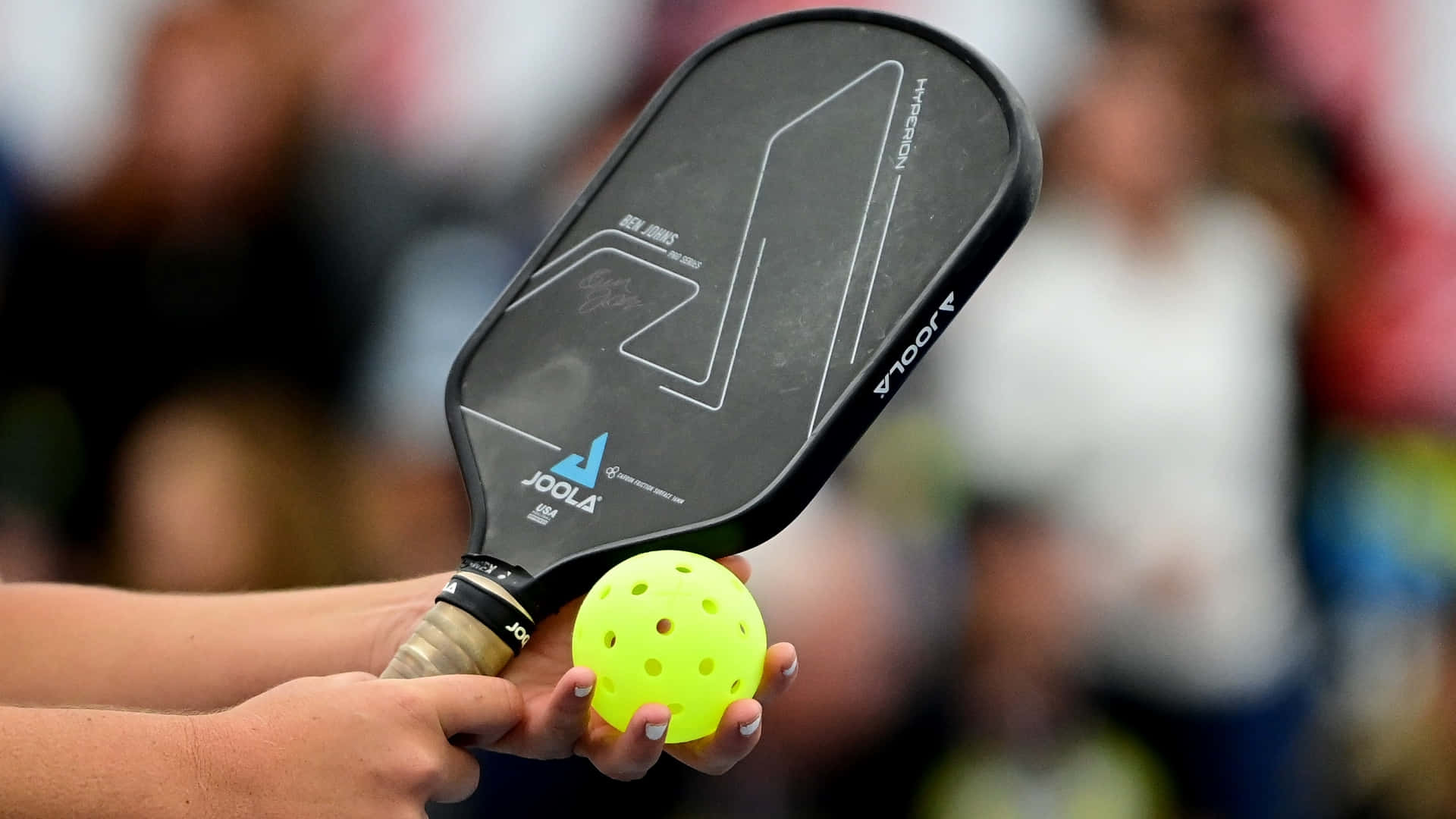 black pickleball paddle, bright yellow ball, blurred crowd background, Full HD Desktop Wallpaper