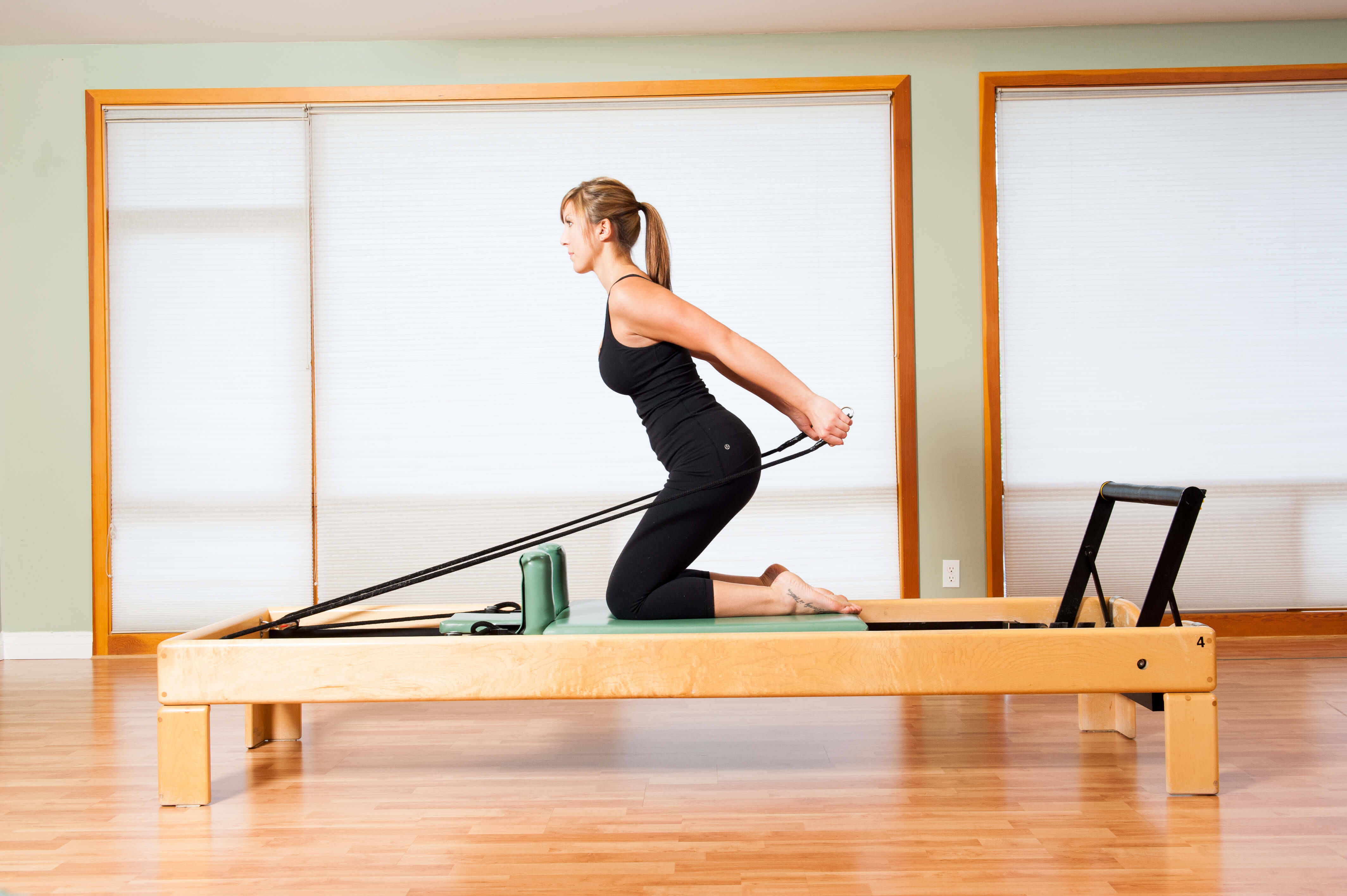 black workout attire, wooden reformer machine, bright studio, 4K Desktop Wallpaper