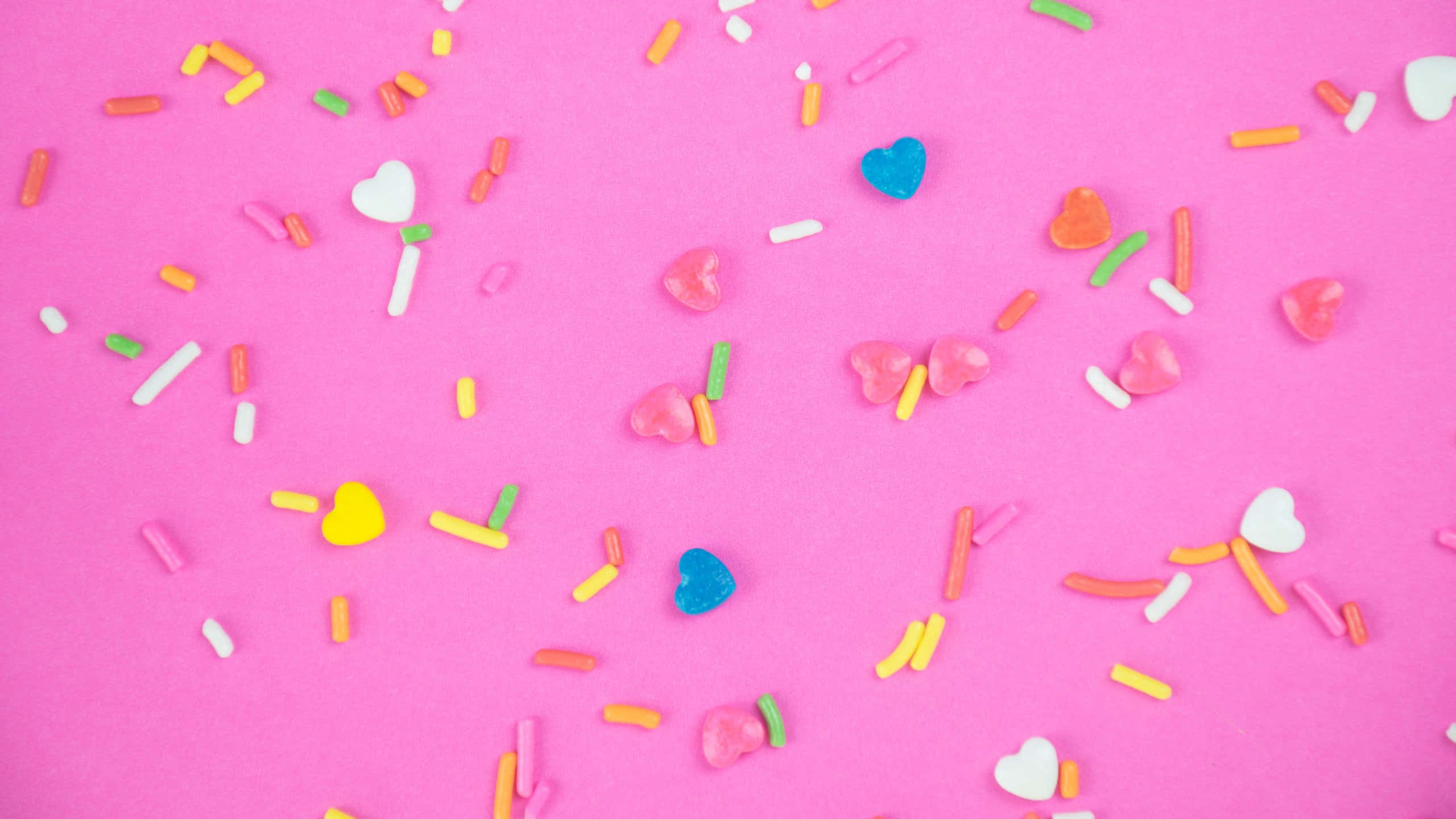 colorful candy sprinkles, pink background, heart-shaped candy sprinkles, 2K Desktop Wallpaper