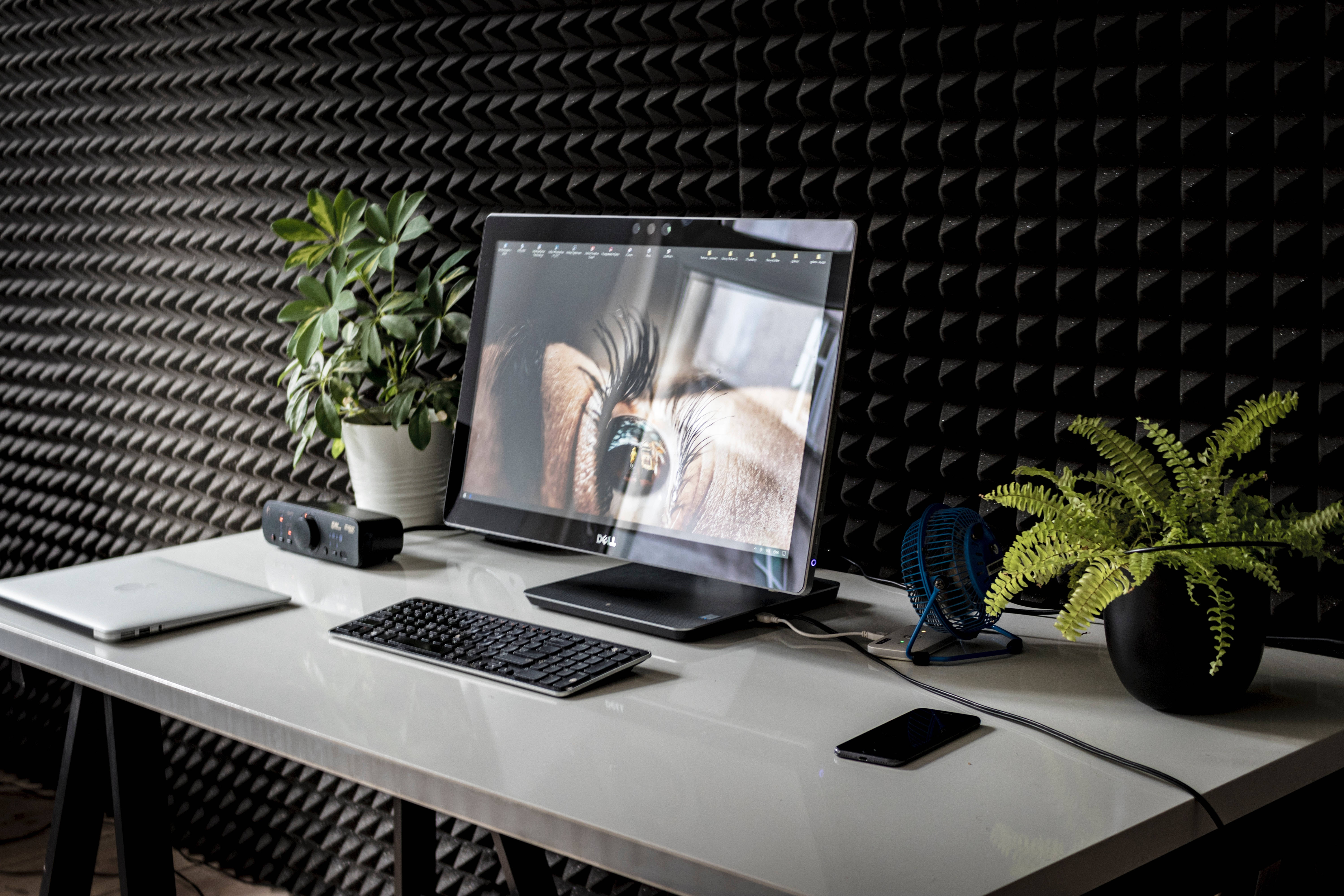 black acoustic wall, sleek white desk, monitor displaying a close-up eye, 5K Desktop Wallpaper