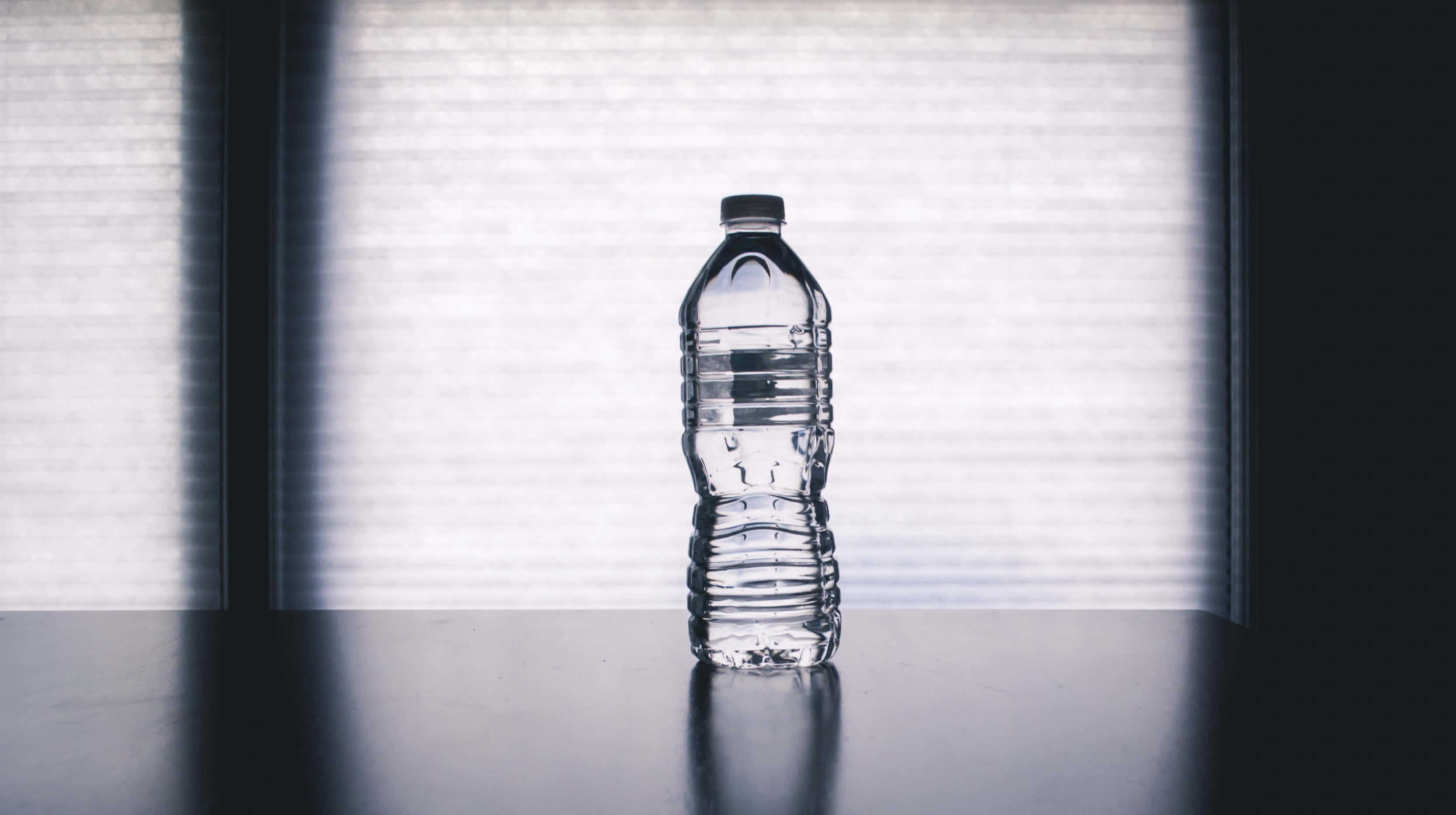 clear plastic water bottle, dark table, softly lit window, 2K Desktop Wallpaper
