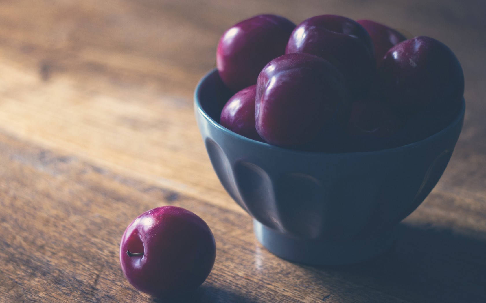 dark blue bowl, glossy purple plums, warm wooden table, HD Desktop Wallpaper