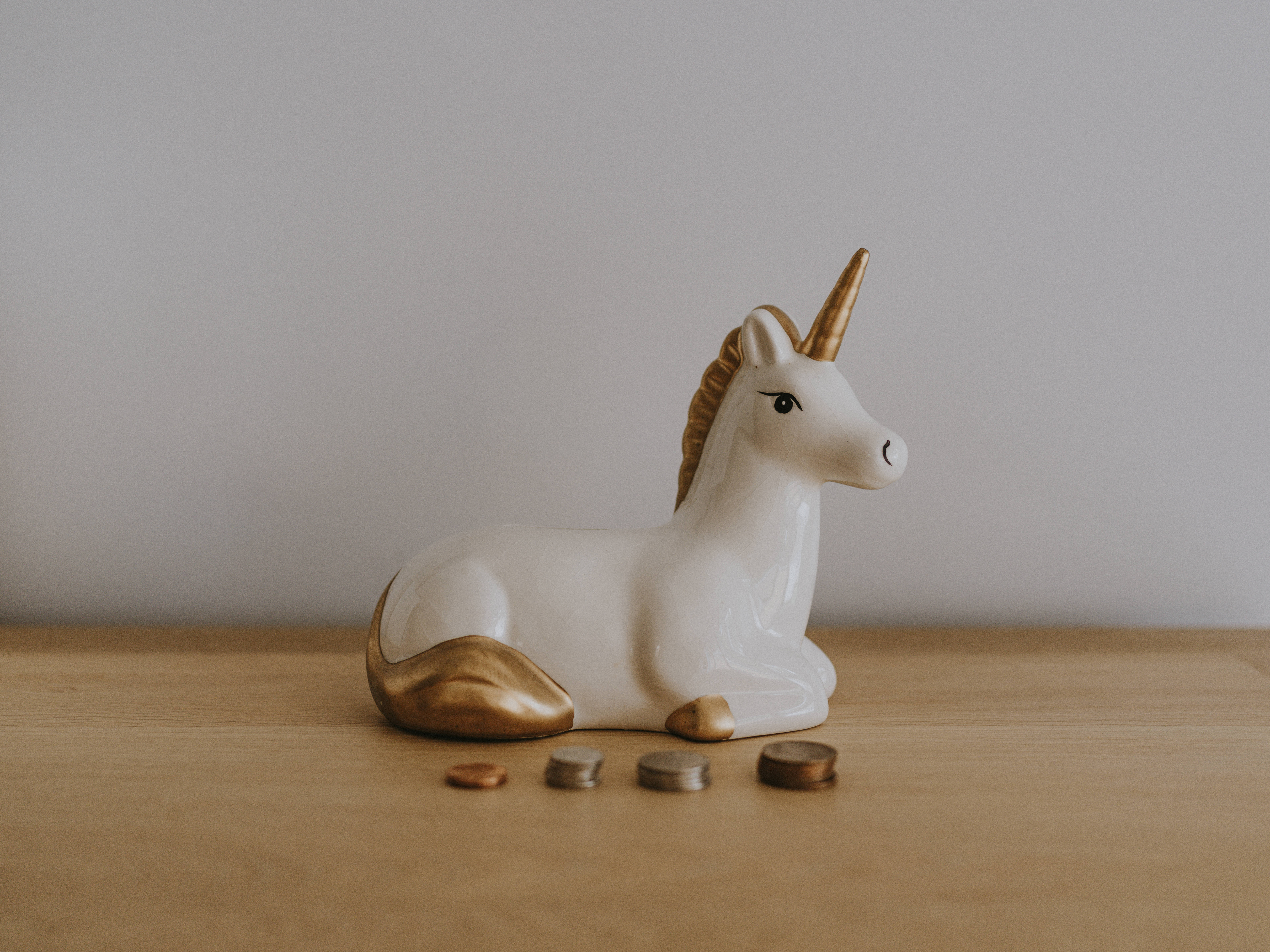 white ceramic unicorn figurine, gold accents, wooden surface, 8K Desktop Wallpaper