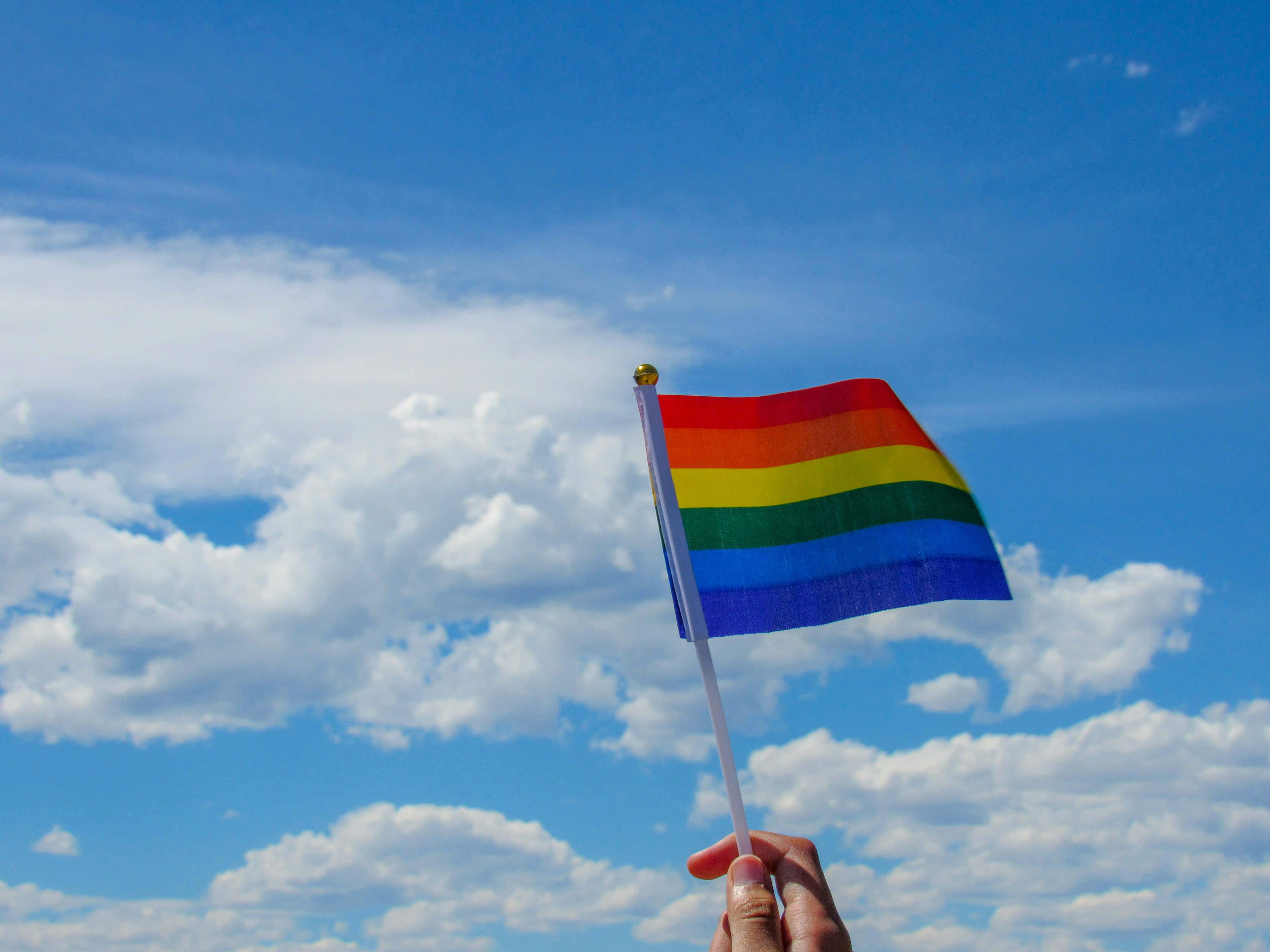 rainbow pride flag, bright blue sky, fluffy white clouds, 4K Desktop Wallpaper