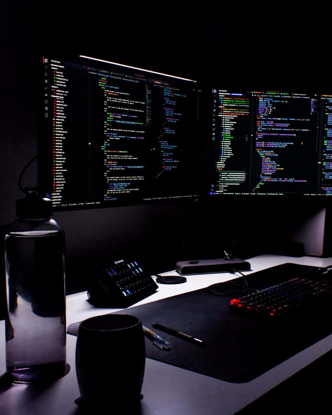 dimly lit desk, dual monitors, colorful code, HD Phone Wallpaper
