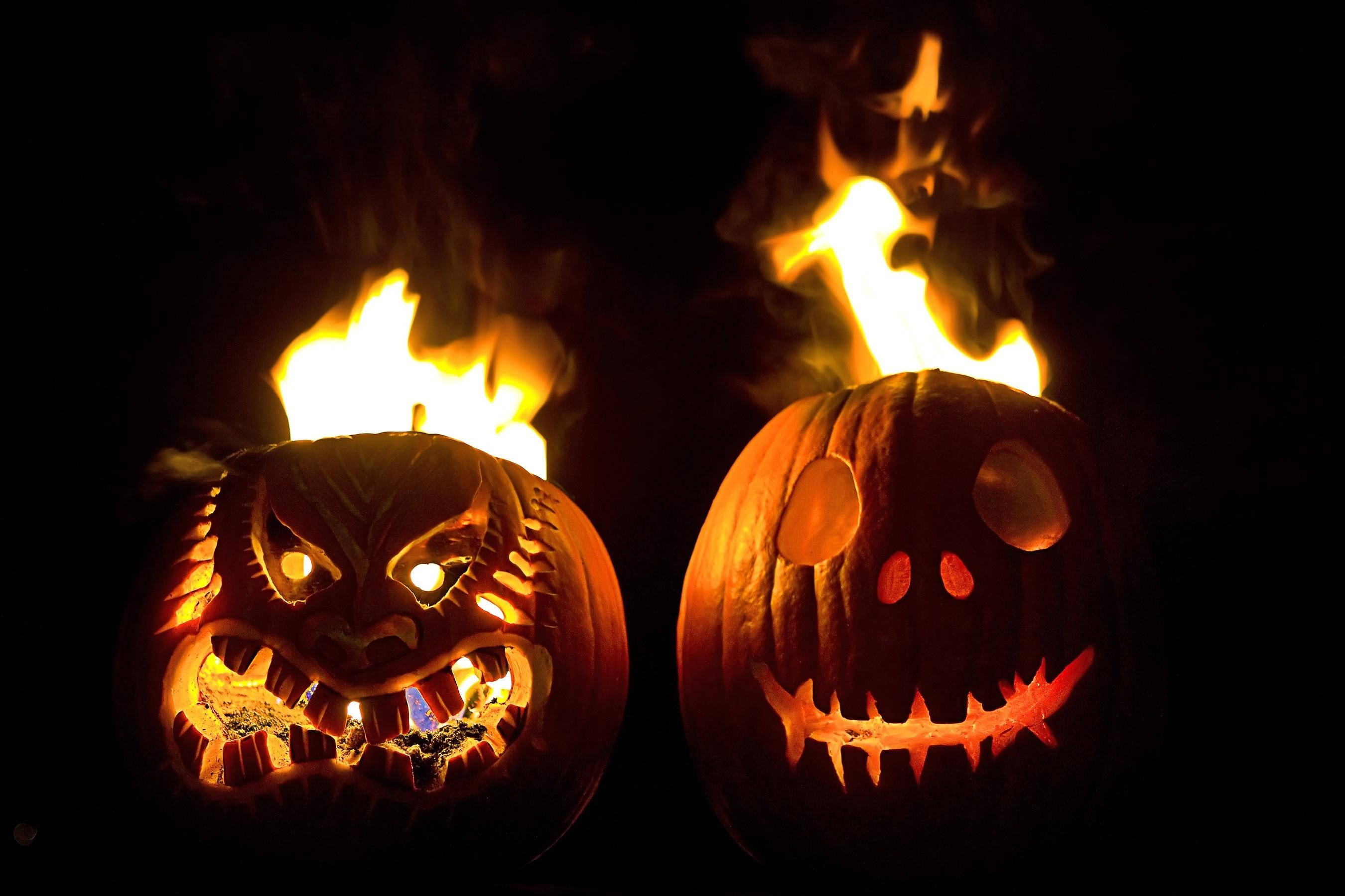 Halloween pumpkins on fire, fierce and goofy faces, flames erupt from their tops, 2K Desktop Wallpaper
