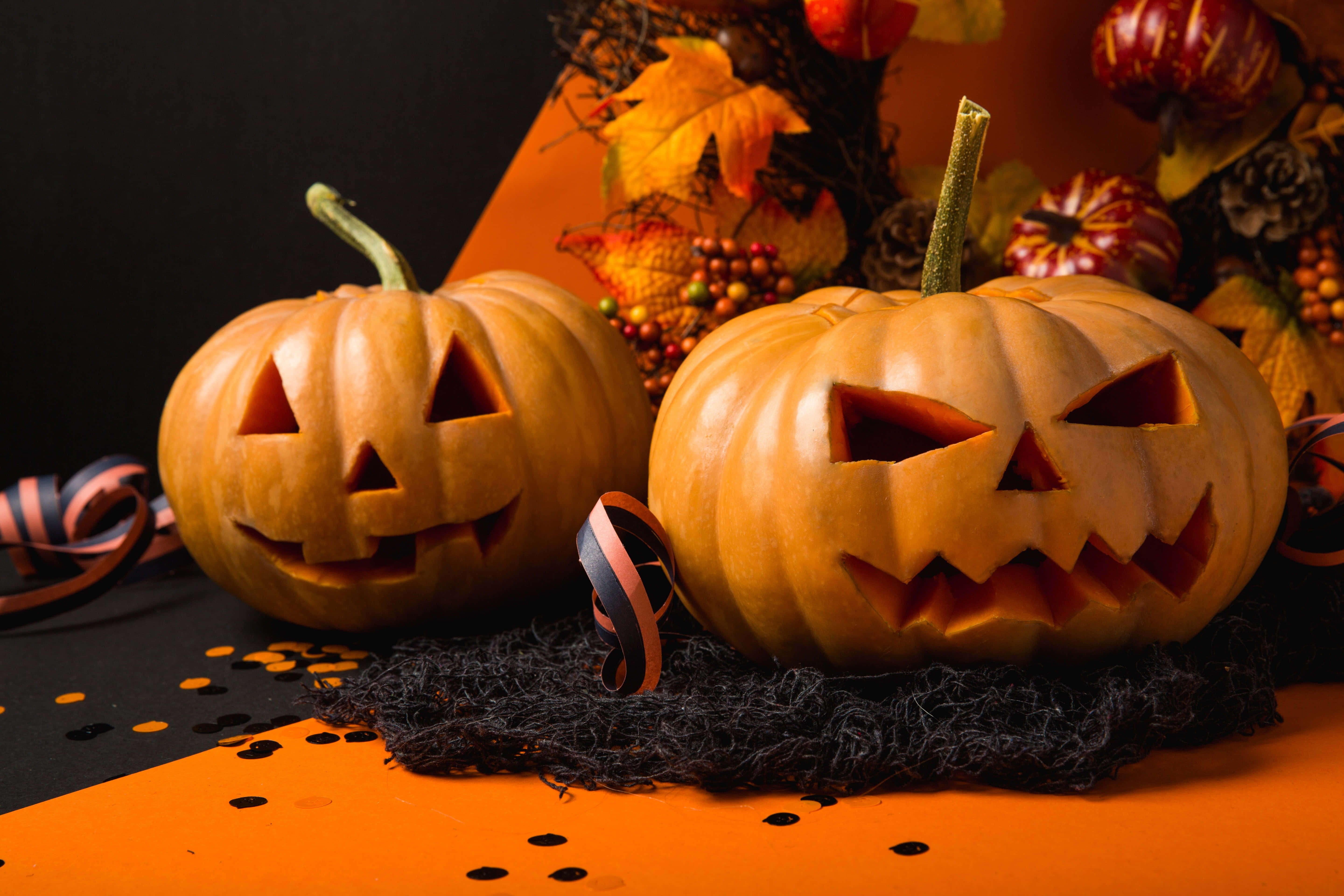 carved jack-o'-lanterns, glowing faces, orange and black Halloween decor, 5K Desktop Wallpaper