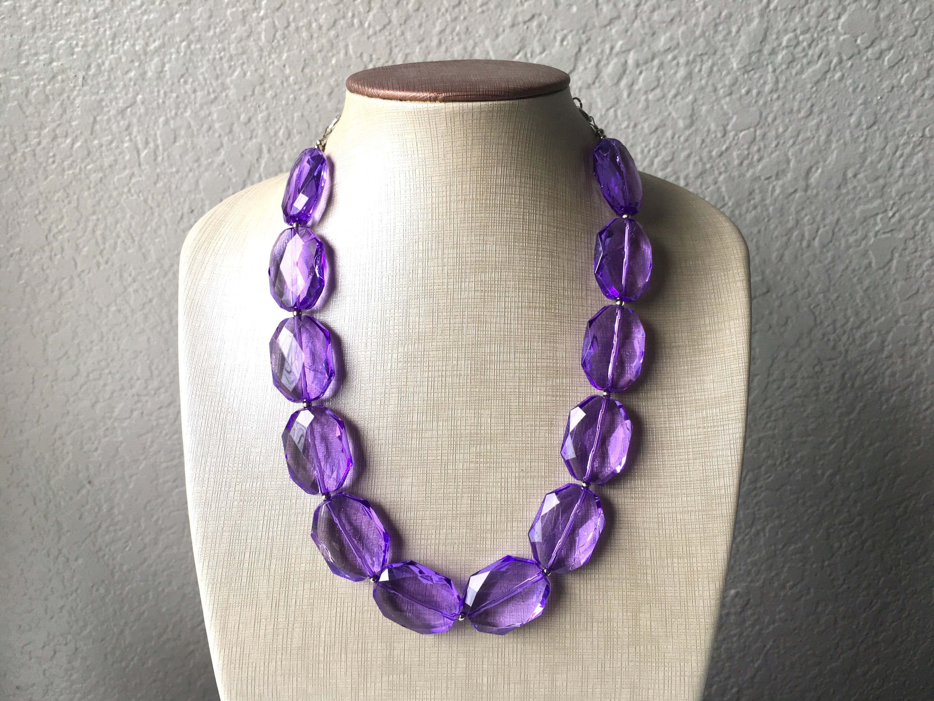 purple faceted bead necklace, beige mannequin bust, textured wall, 2K Desktop Wallpaper