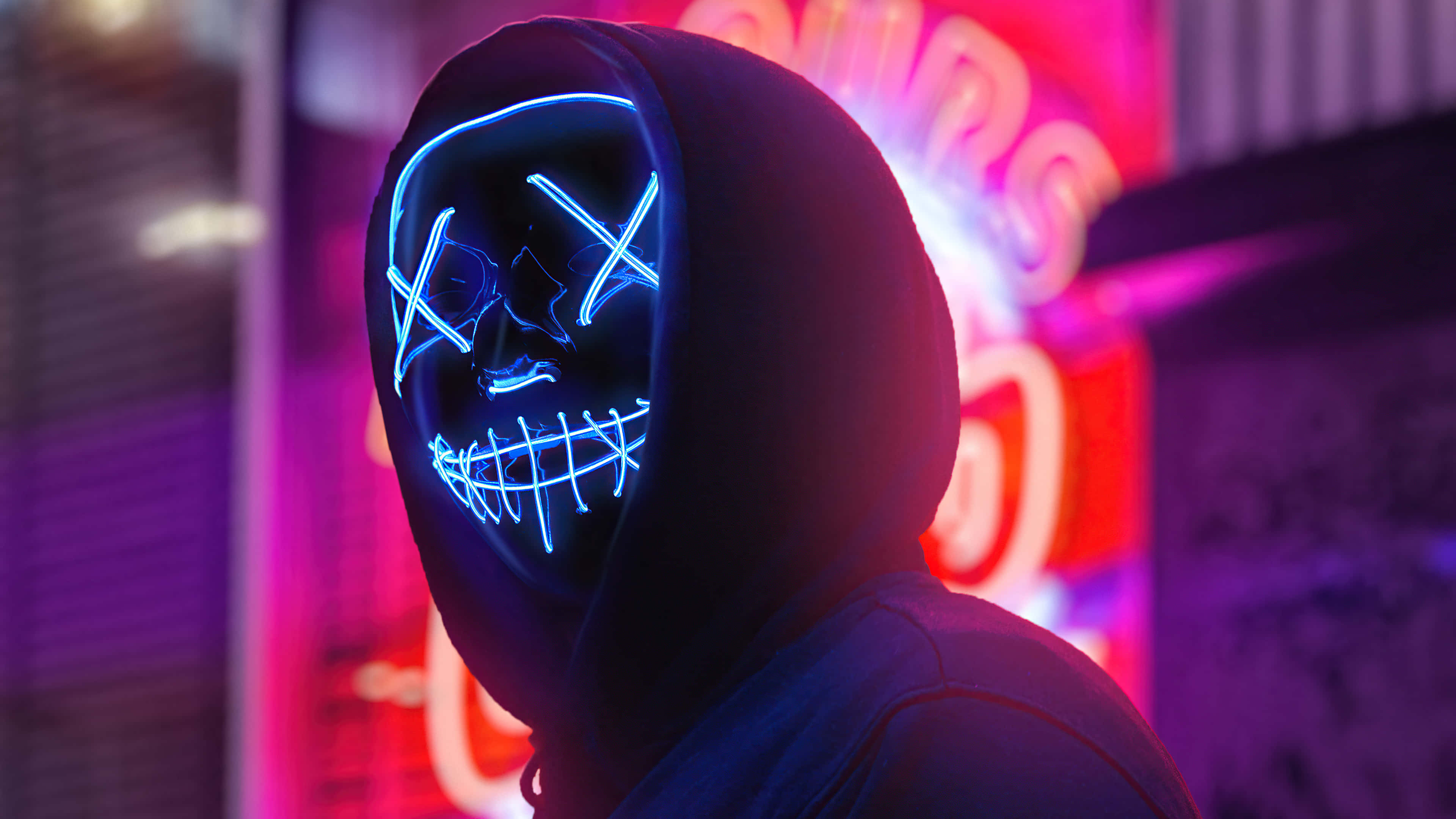 Purple Jacket, glowing blue LED skull mask, vibrant neon-lit urban backdrop, 4K Desktop Wallpaper