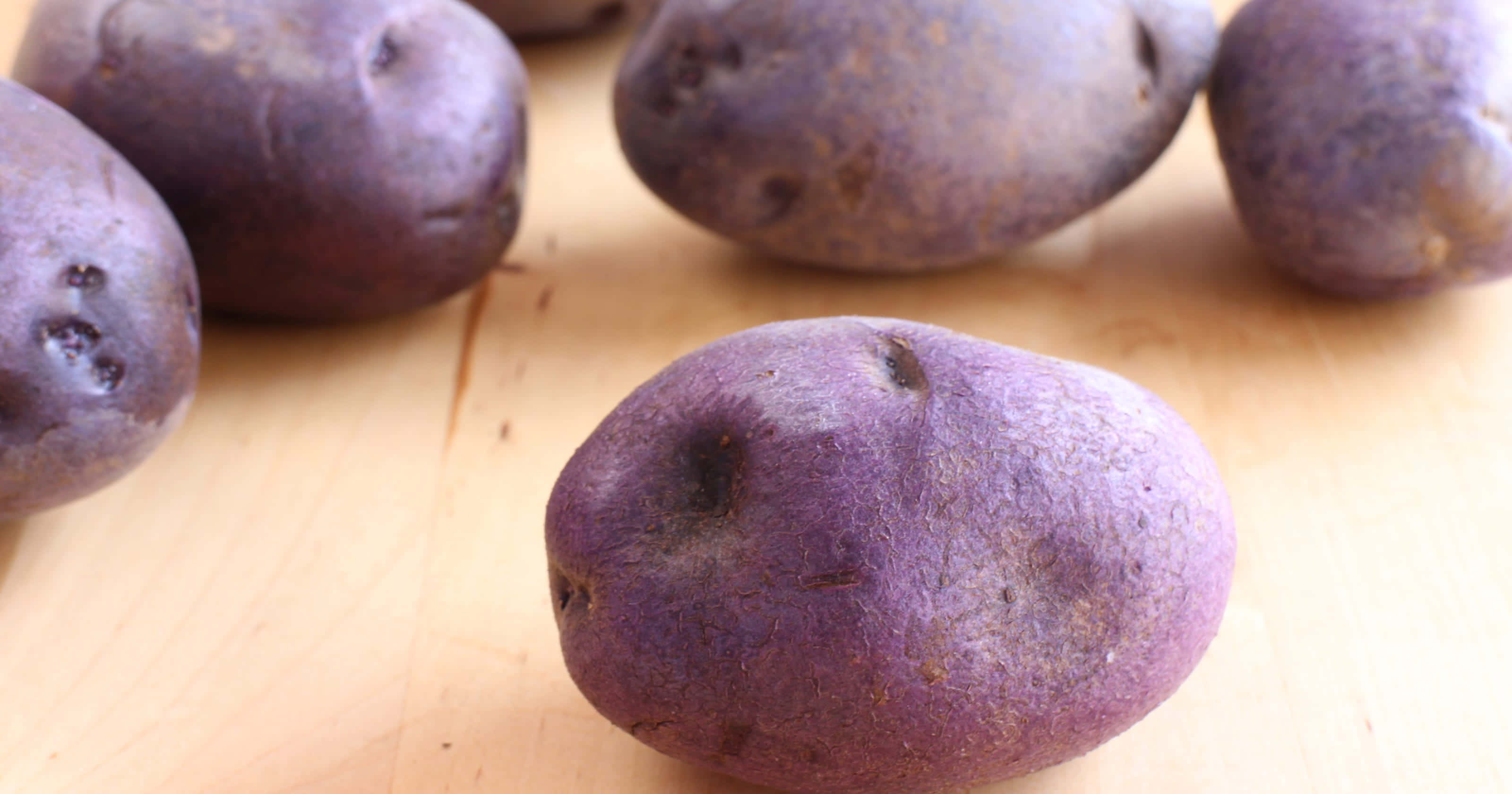 purple potatoes, light wooden surface, soft natural lighting, 2K Desktop Wallpaper
