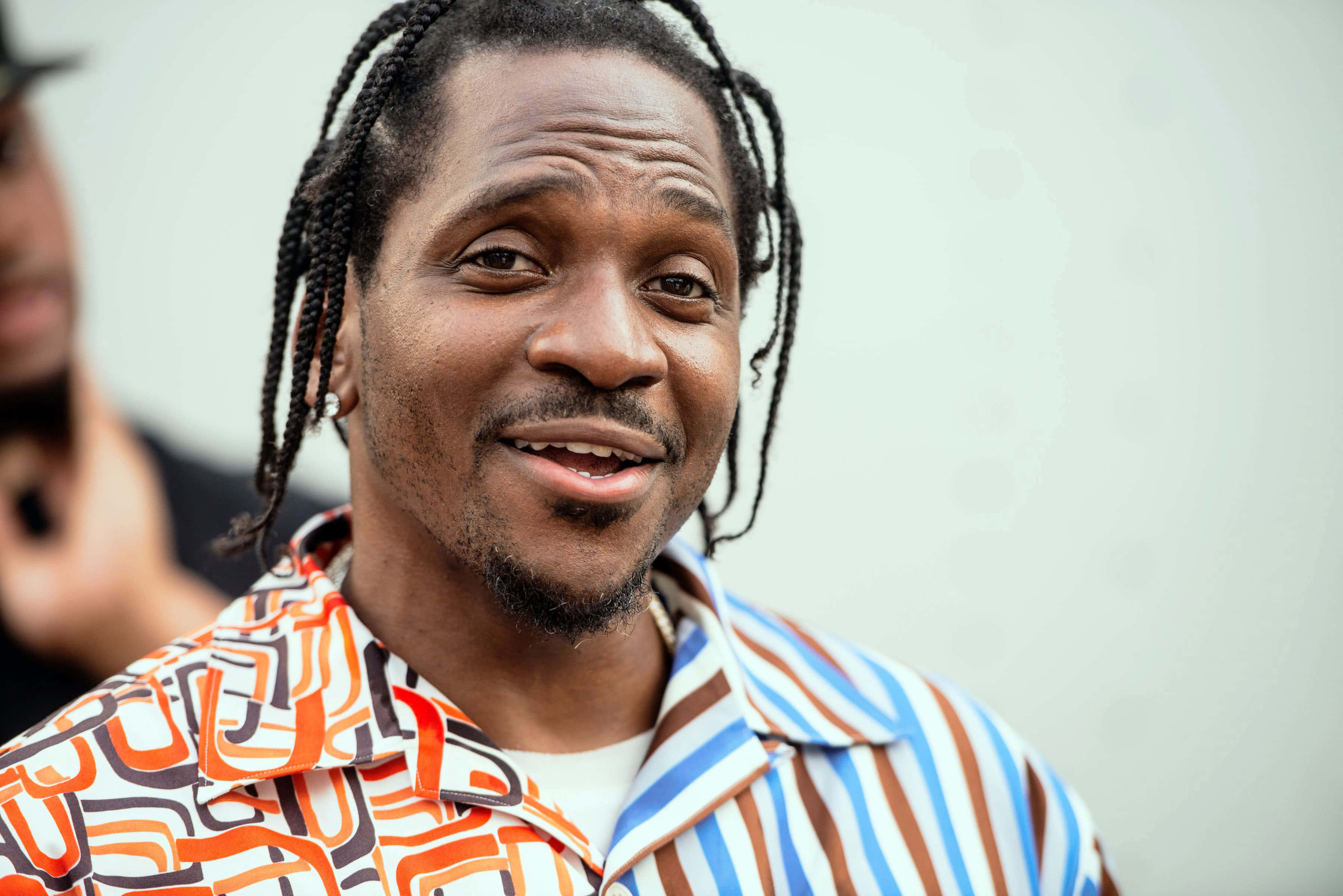 Pusha T, braided hair, vibrant orange brown and blue patterned shirt, 2K Desktop Wallpaper