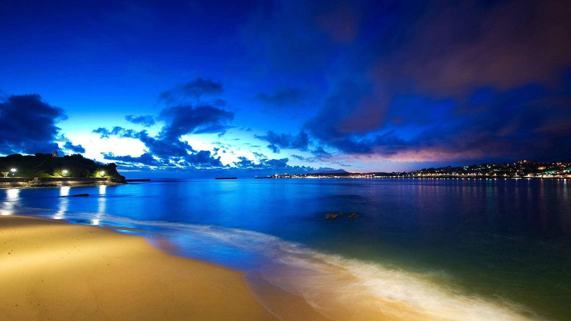 quiet seaside at night, glowing amber sand, calm blue waters, Full HD Desktop Wallpaper