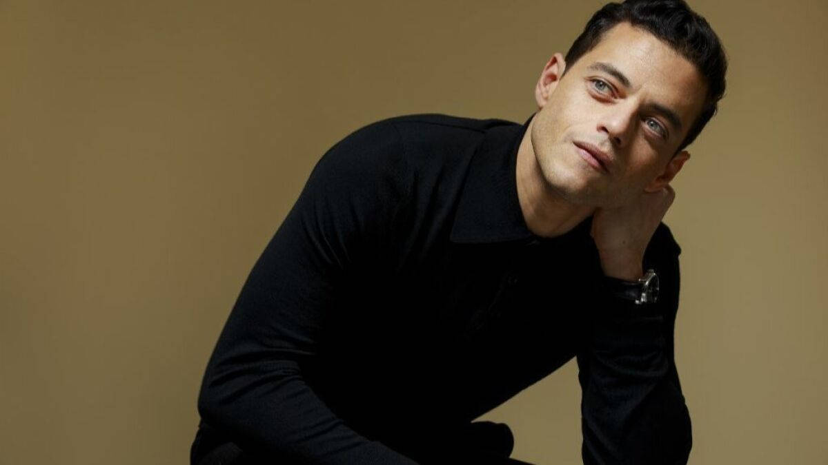 Rami Malek, black shirt, warm beige wall, SD Desktop Wallpaper