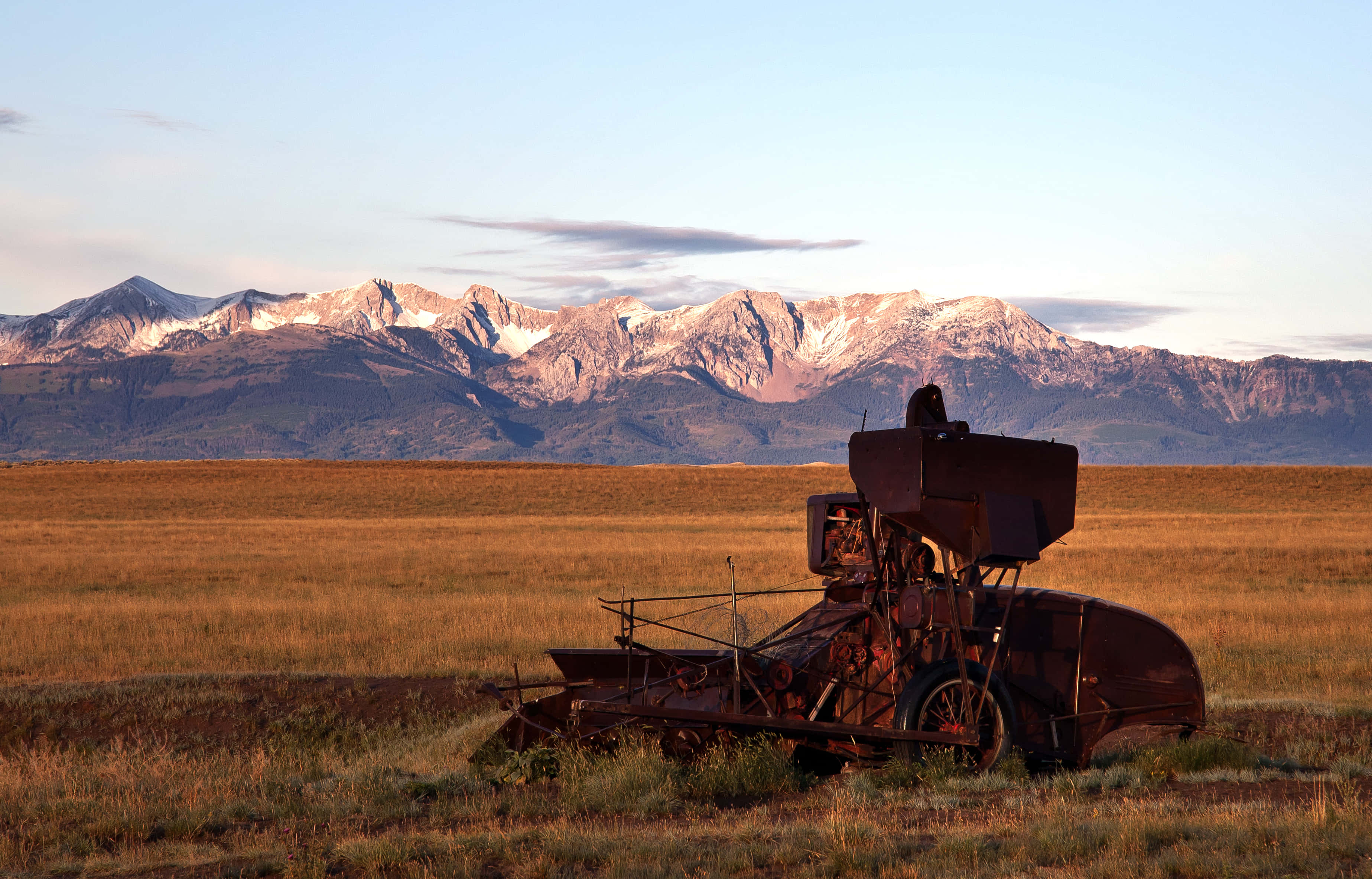 rusted vintage combine harvester, golden field, snow-capped mountains, 2K Desktop Wallpaper