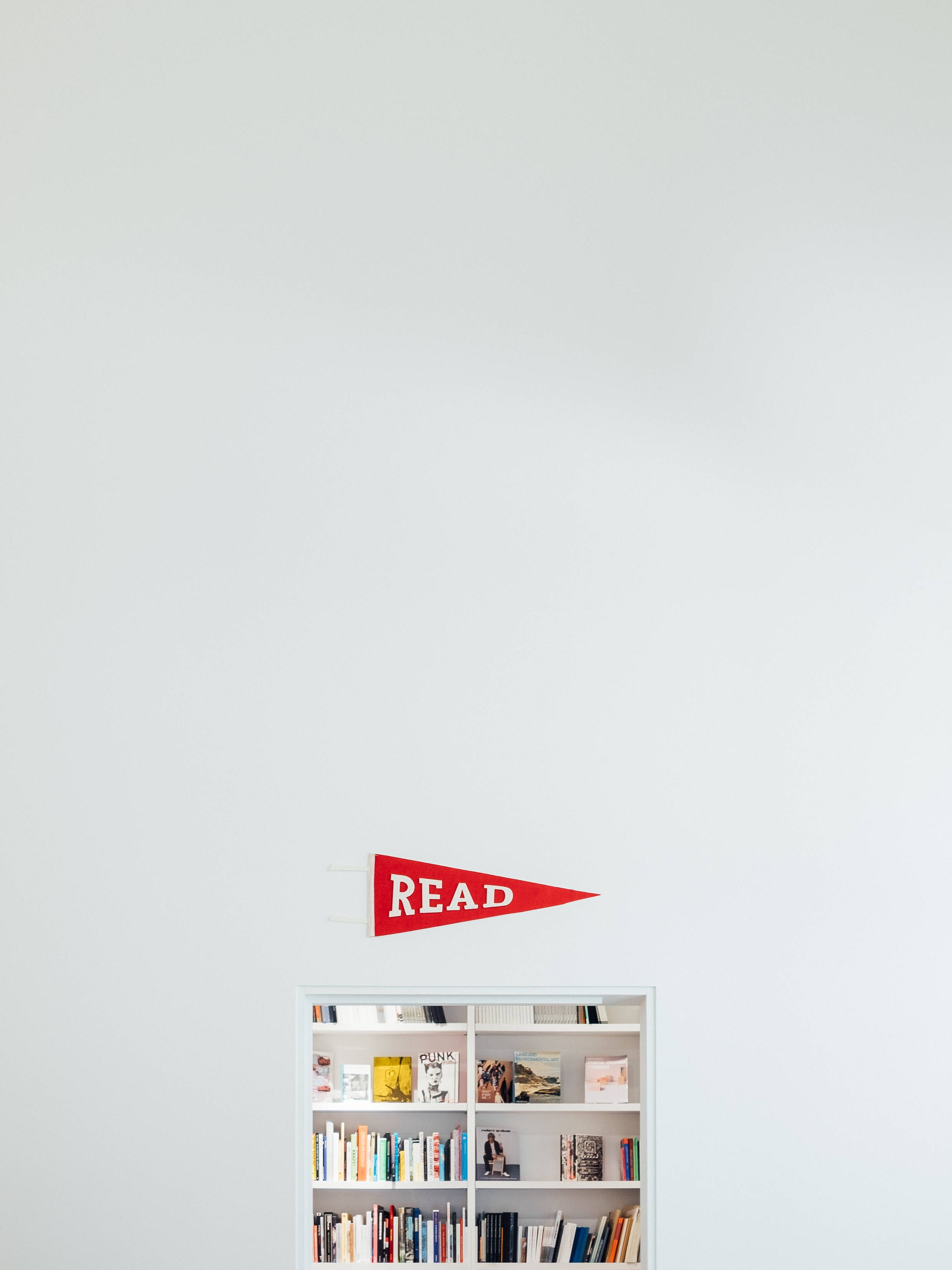minimalist white room, red pennant reading READ, bookshelf, 2K Phone Wallpaper