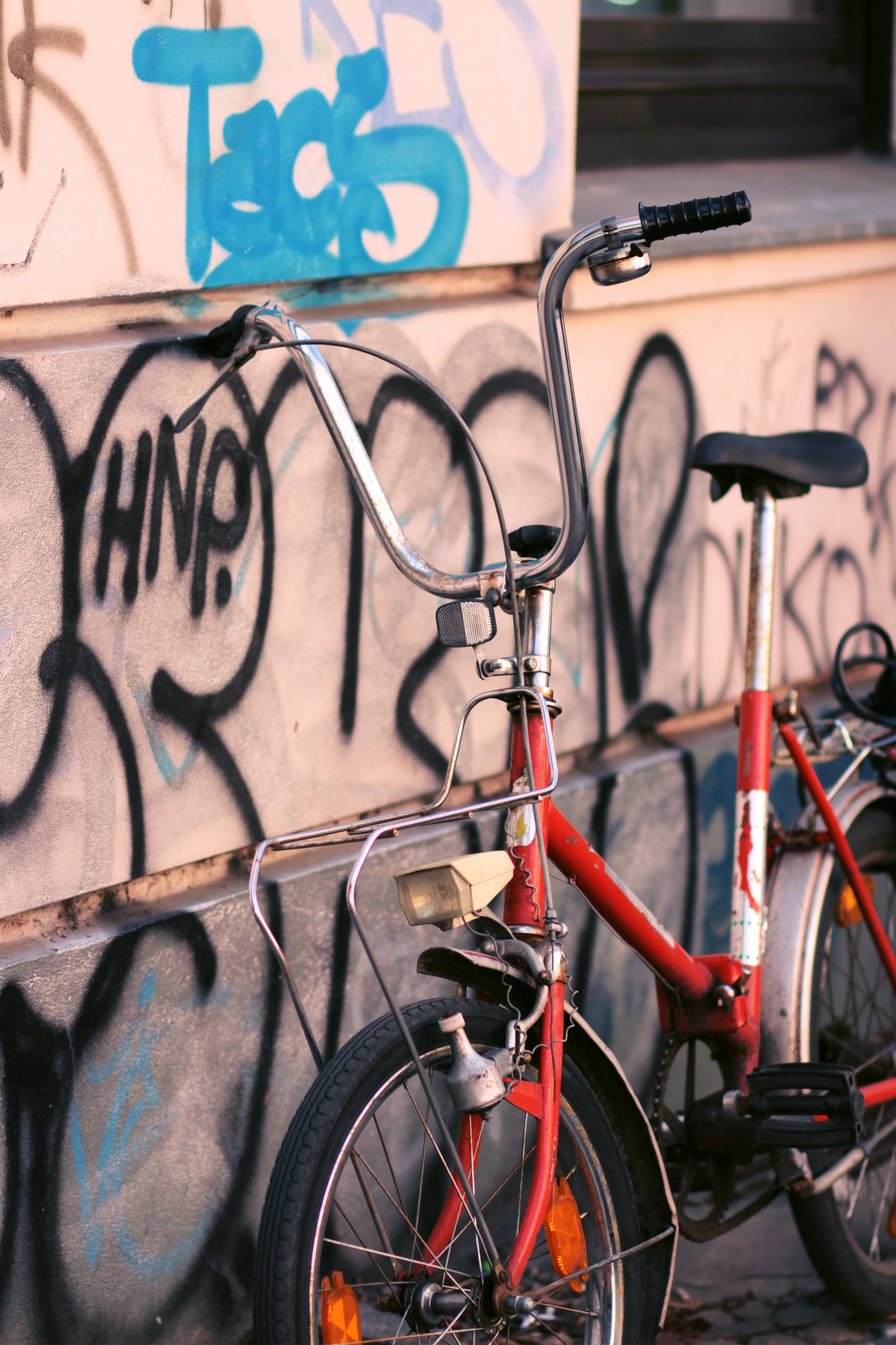 red bike, graffiti-covered wall, golden hour light, 5K Phone Wallpaper