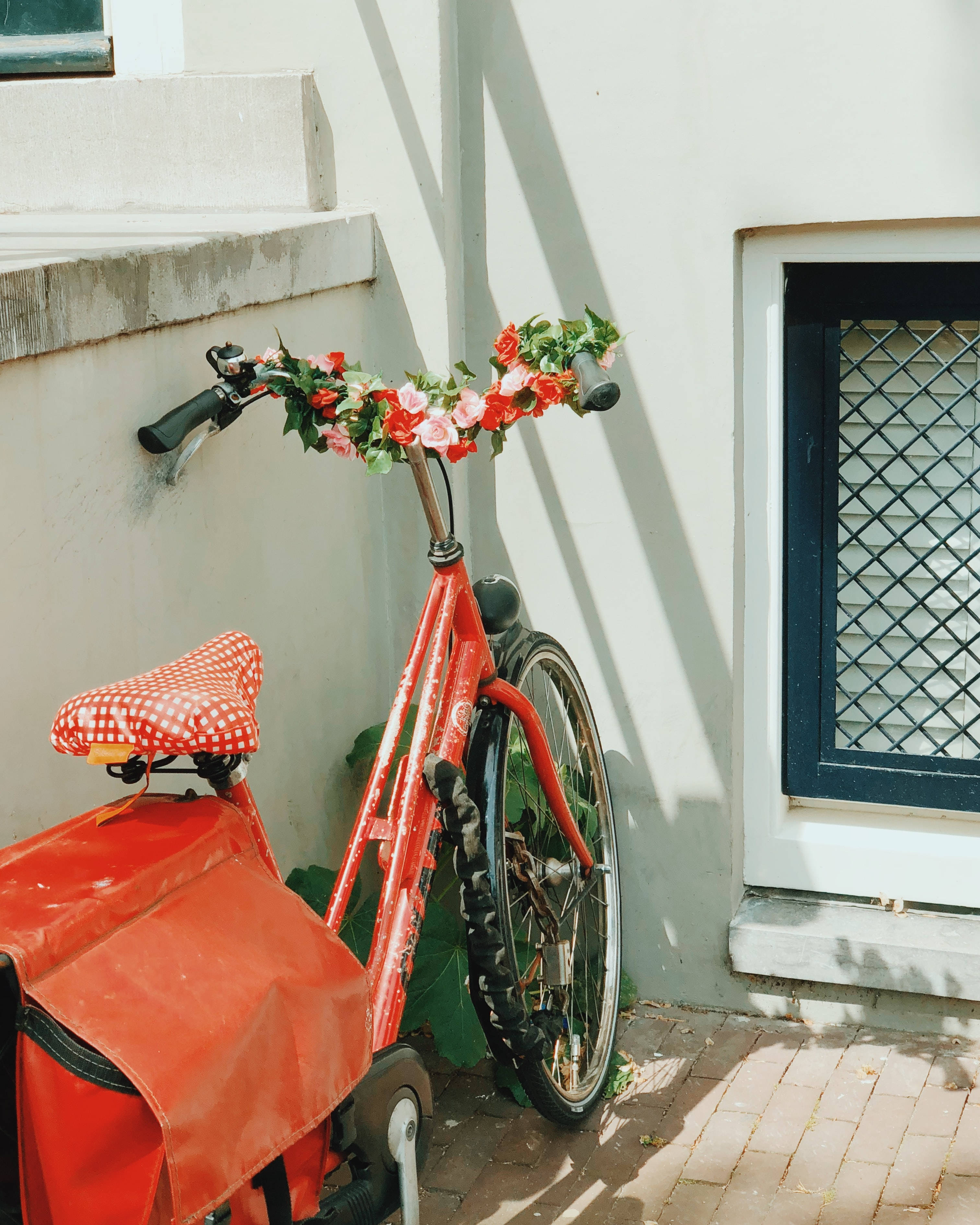 Red Bike, floral garland, sunlit white wall, 2K Phone Wallpaper