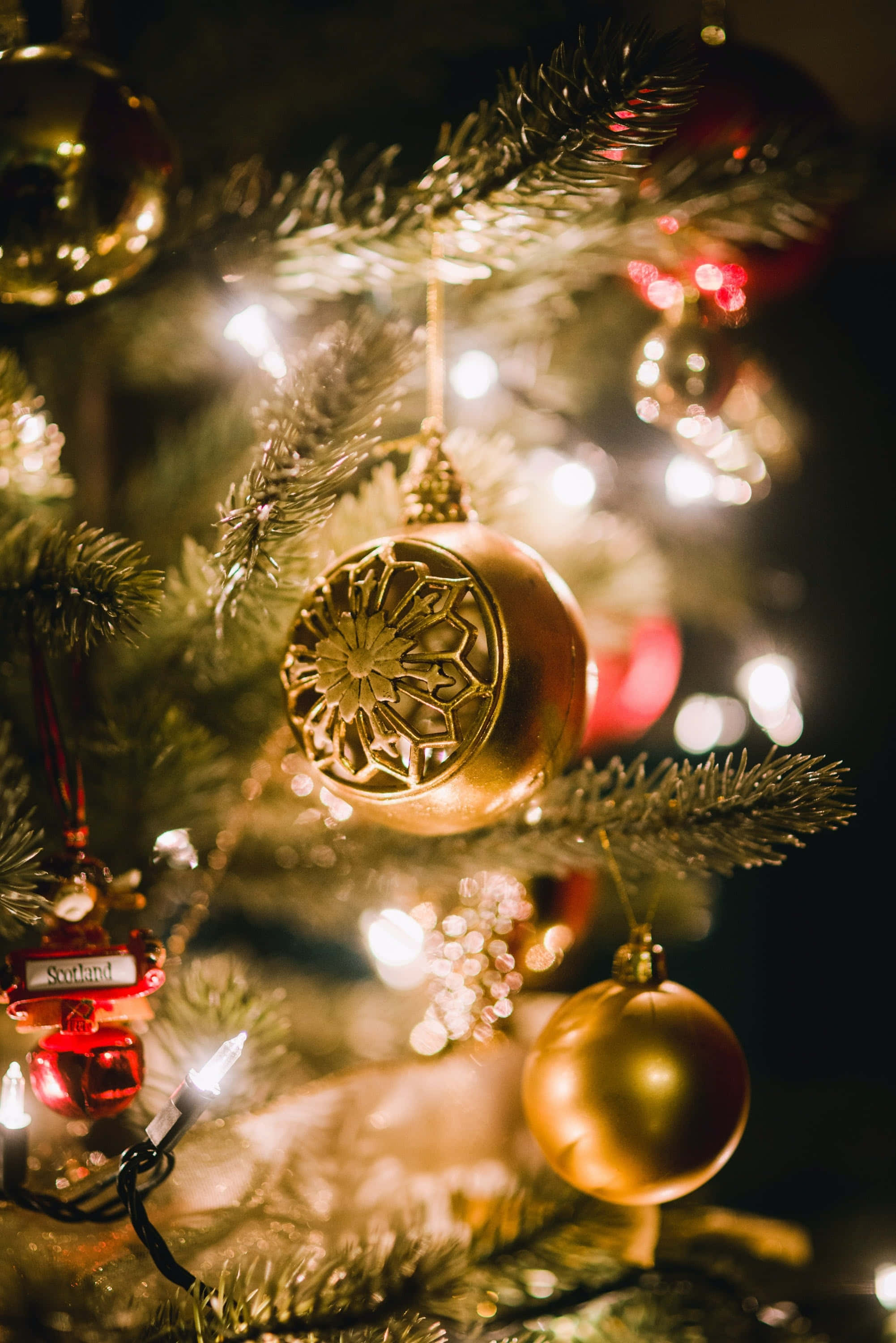Red Christmas iPhone, golden ornaments, twinkling lights, 2K Phone Wallpaper