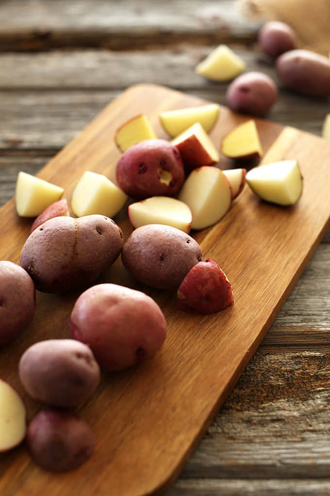 red potatoes, rustic wooden cutting board, warm natural lighting, SD Phone Wallpaper