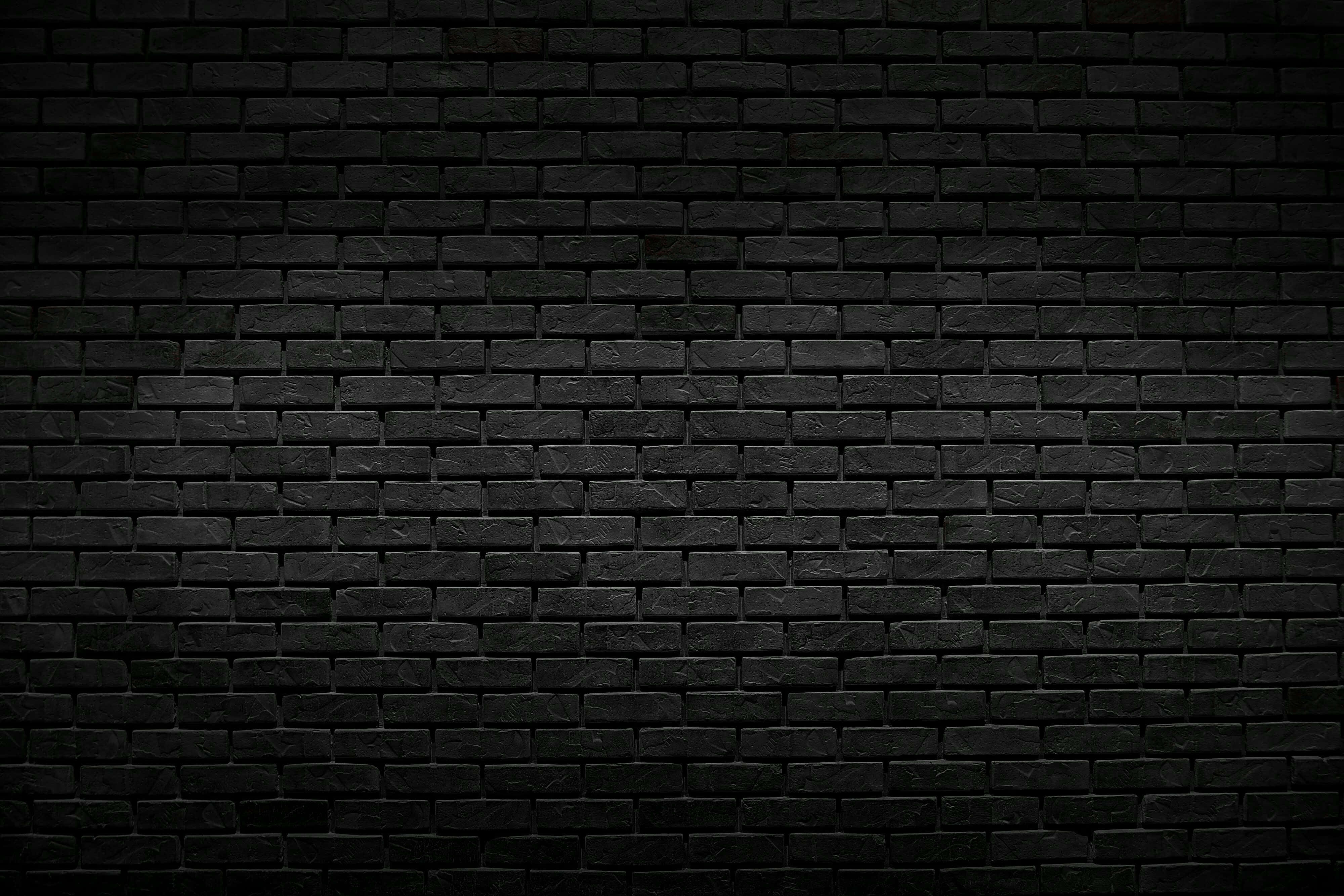 dark textured brick wall, subtle lighting variations, monochrome, 4K Desktop Wallpaper