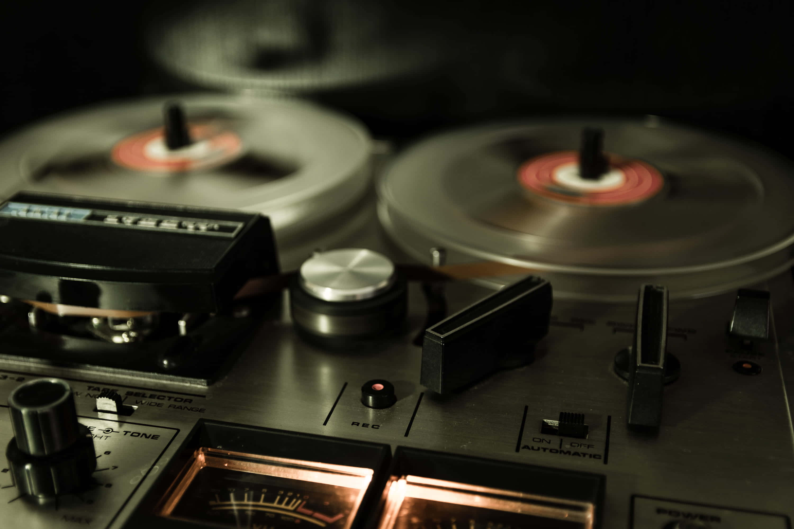 reel-to-reel tape recorder, spinning reels, glowing meters, 2K Desktop Wallpaper