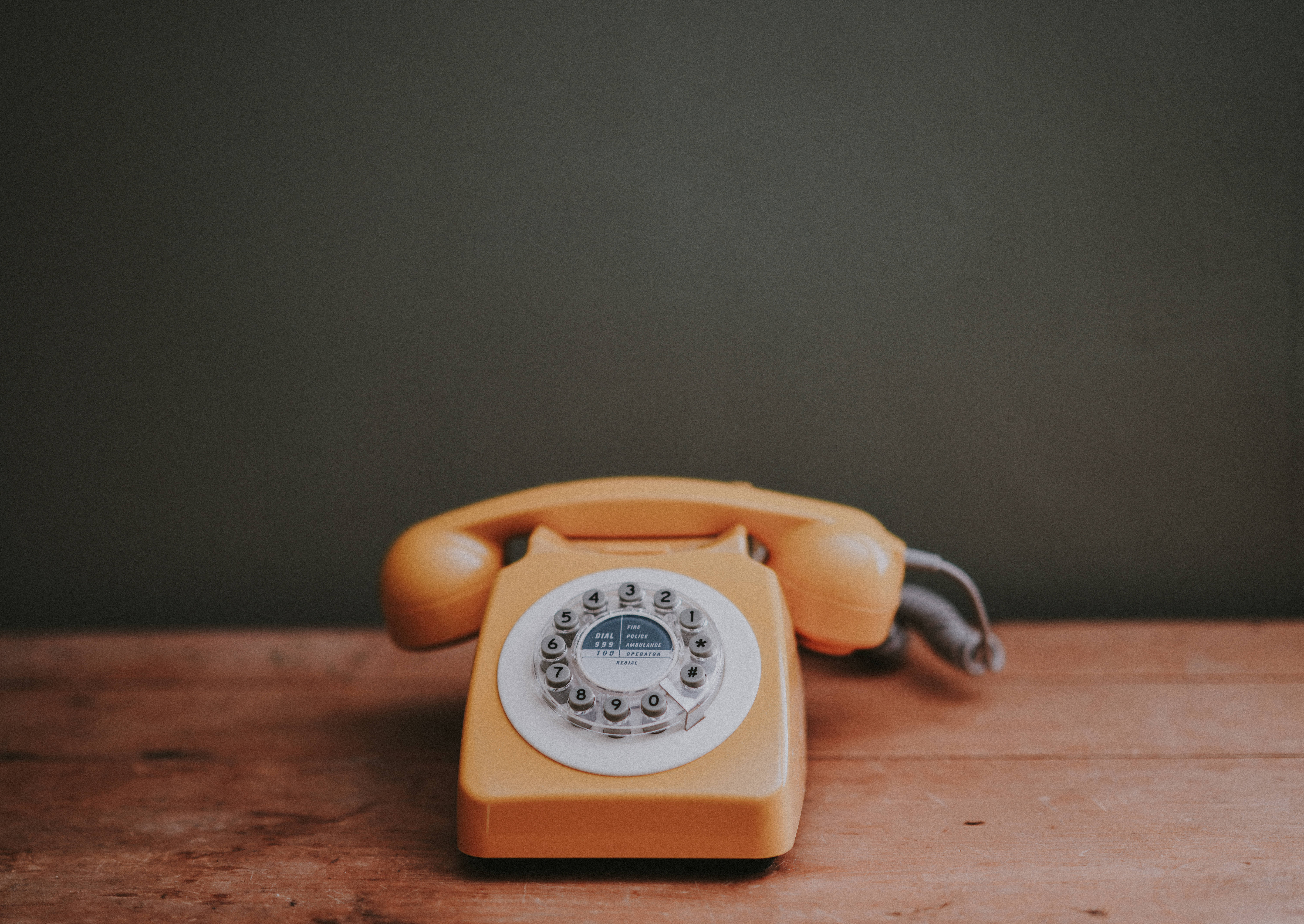 vintage yellow rotary telephone, rustic wooden table, muted green wall, 5K Desktop Wallpaper