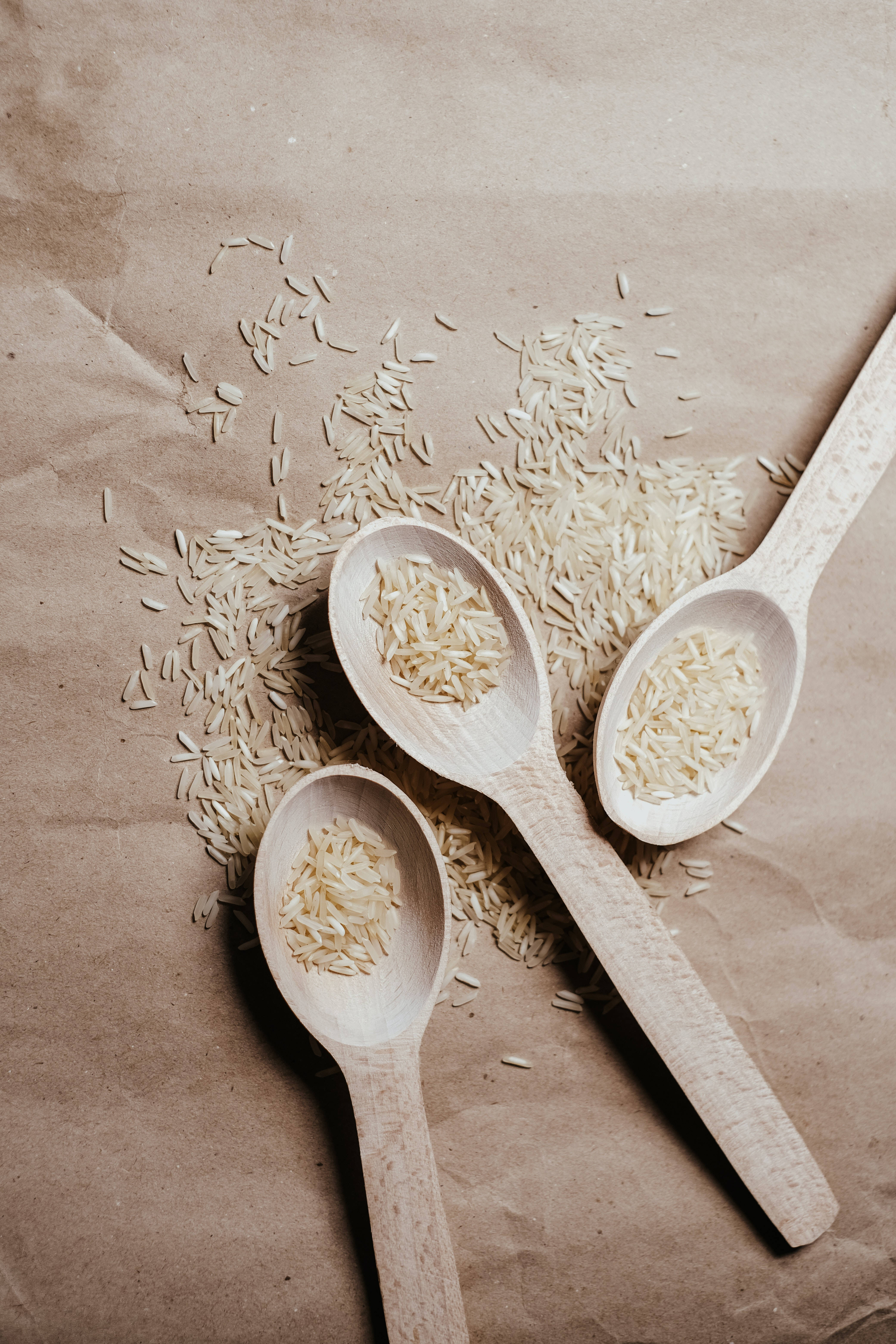 three wooden spoons, uncooked rice grains, crinkled brown paper, 5K Phone Wallpaper