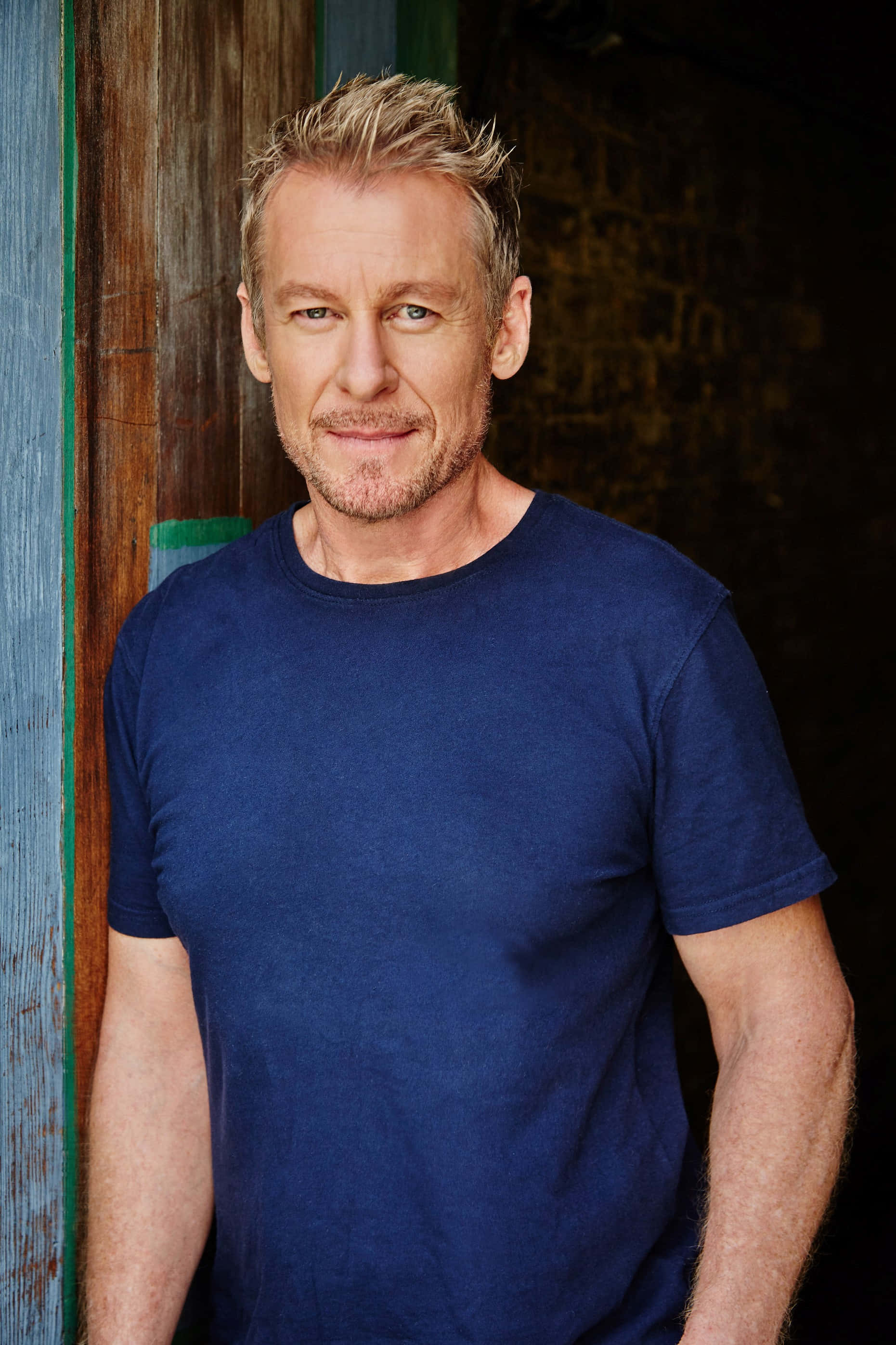 Richard Roxburgh, blue t-shirt, weathered wooden door, 2K Phone Wallpaper