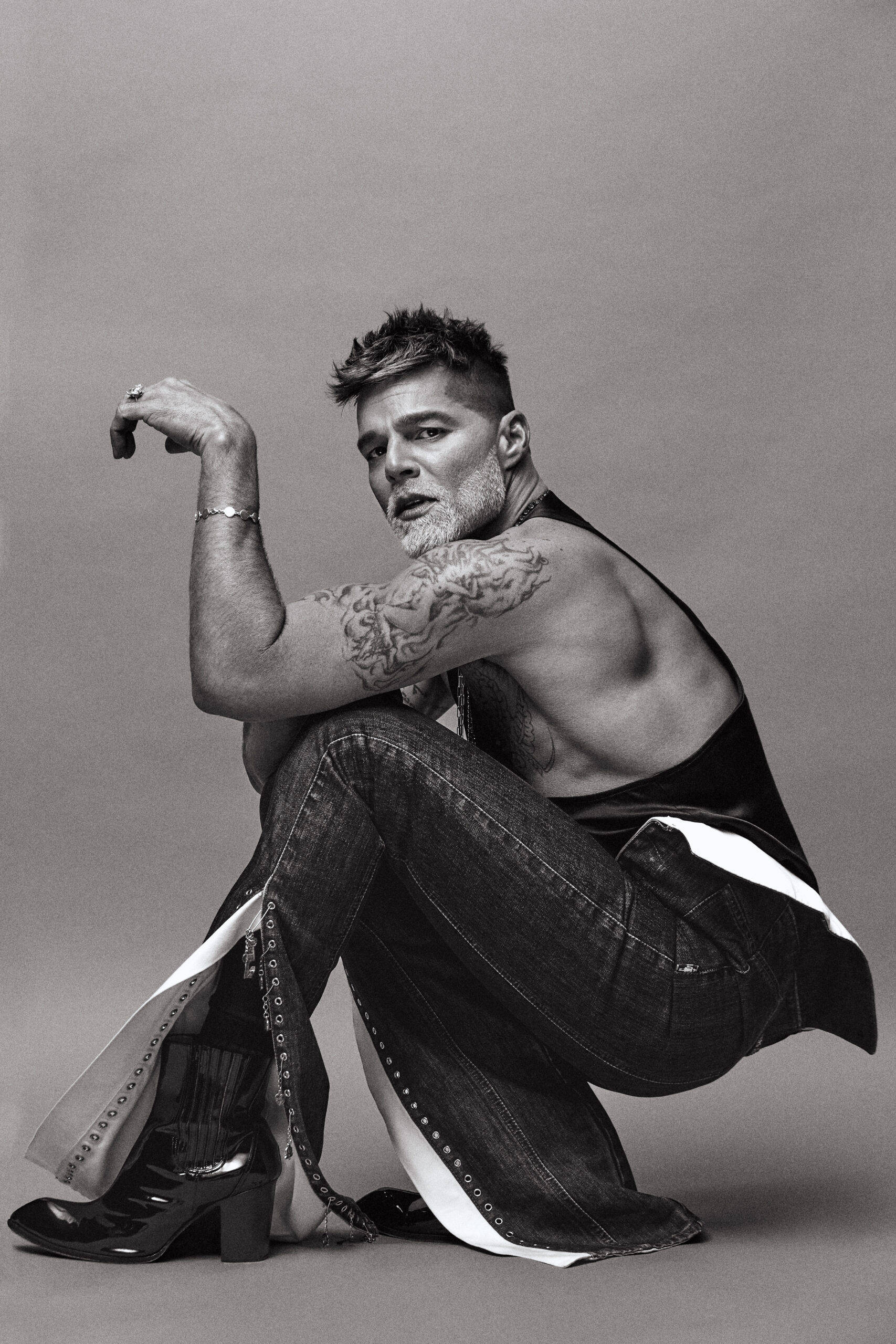 Ricky Martin, crouching down, black and white studio lighting, 2K Phone Wallpaper