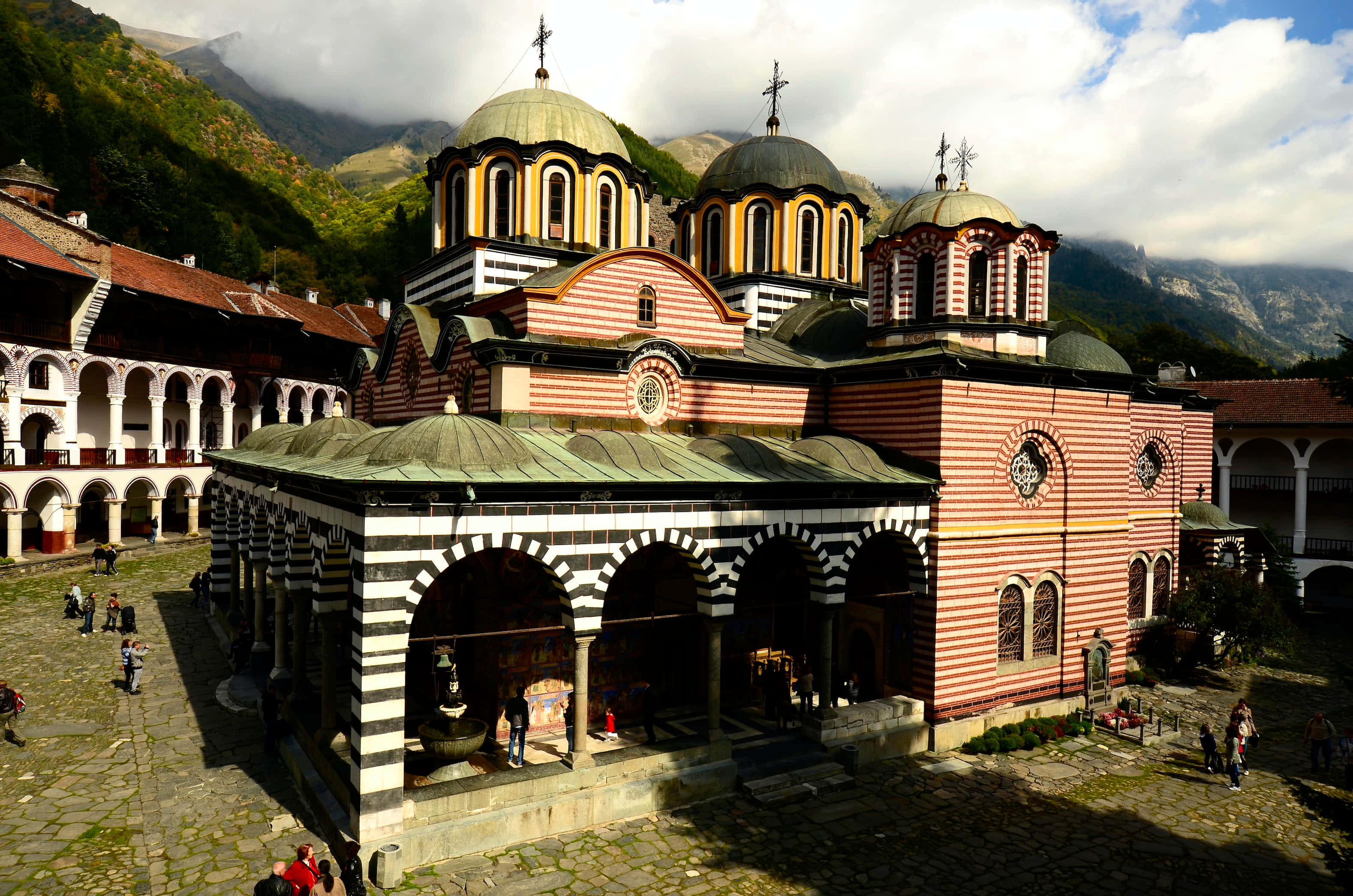 Rila Monastery, striped pink and white walls, golden domes, 2K Desktop Wallpaper