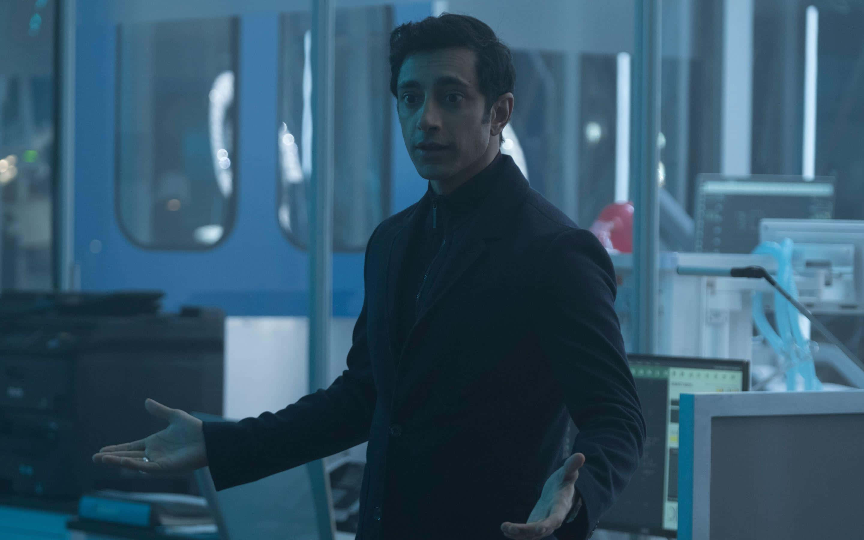 Riz Ahmed, dark suit, futuristic lab, 2K Desktop Wallpaper