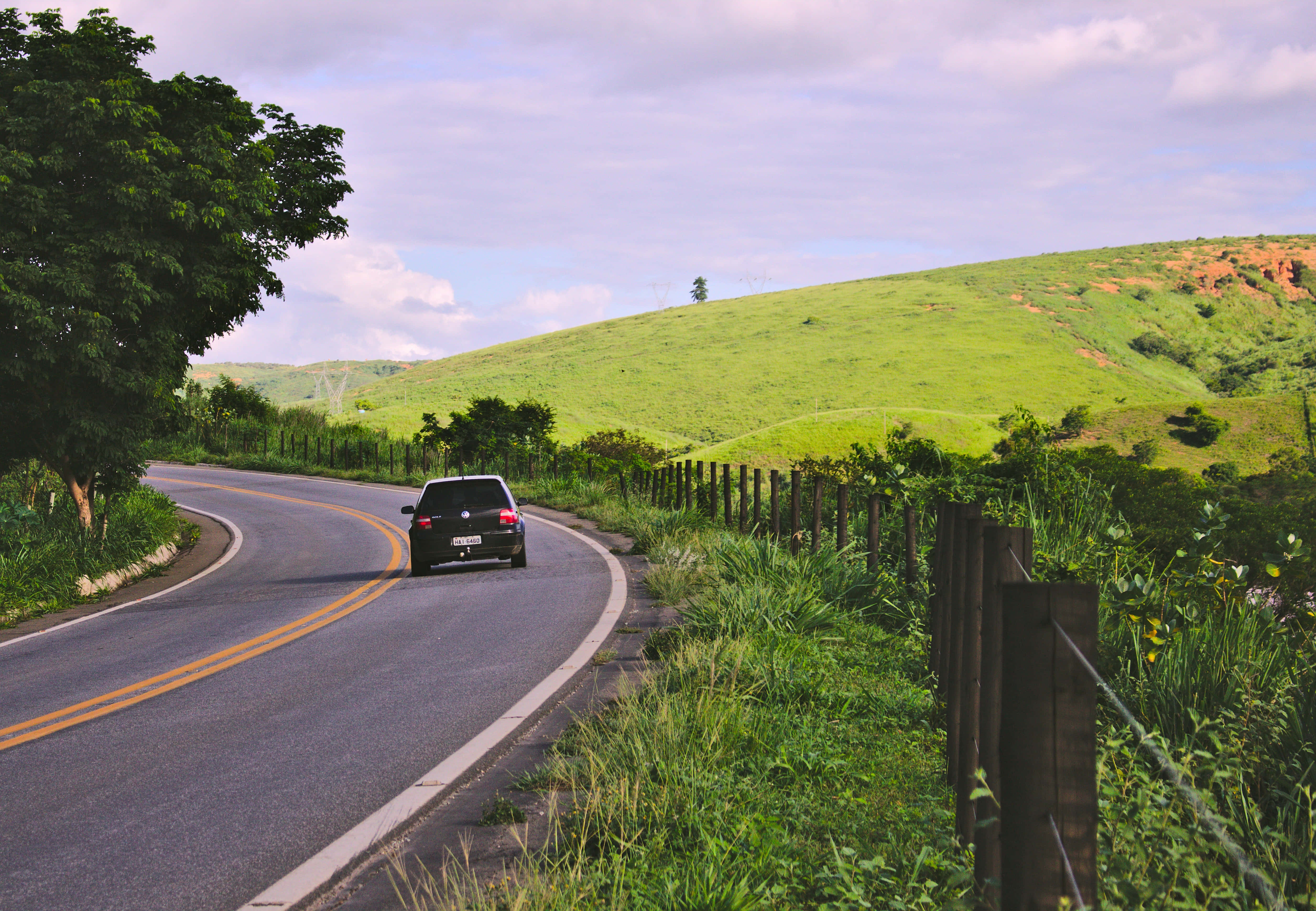black car, winding asphalt road, lush green hills, 4K Desktop Wallpaper
