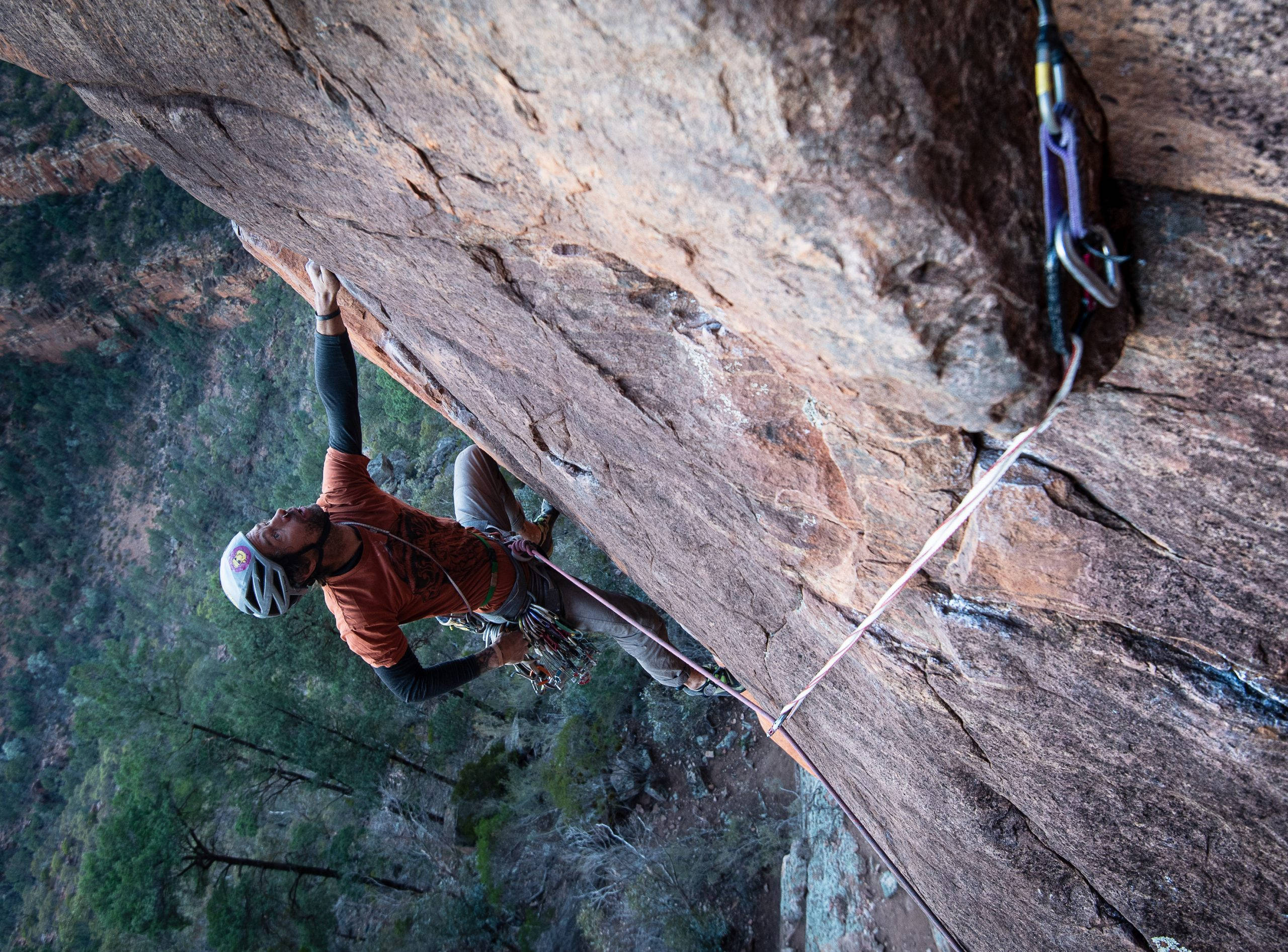 flip rock structure, orange shirt, steep rocky cliff face, 2K Desktop Wallpaper