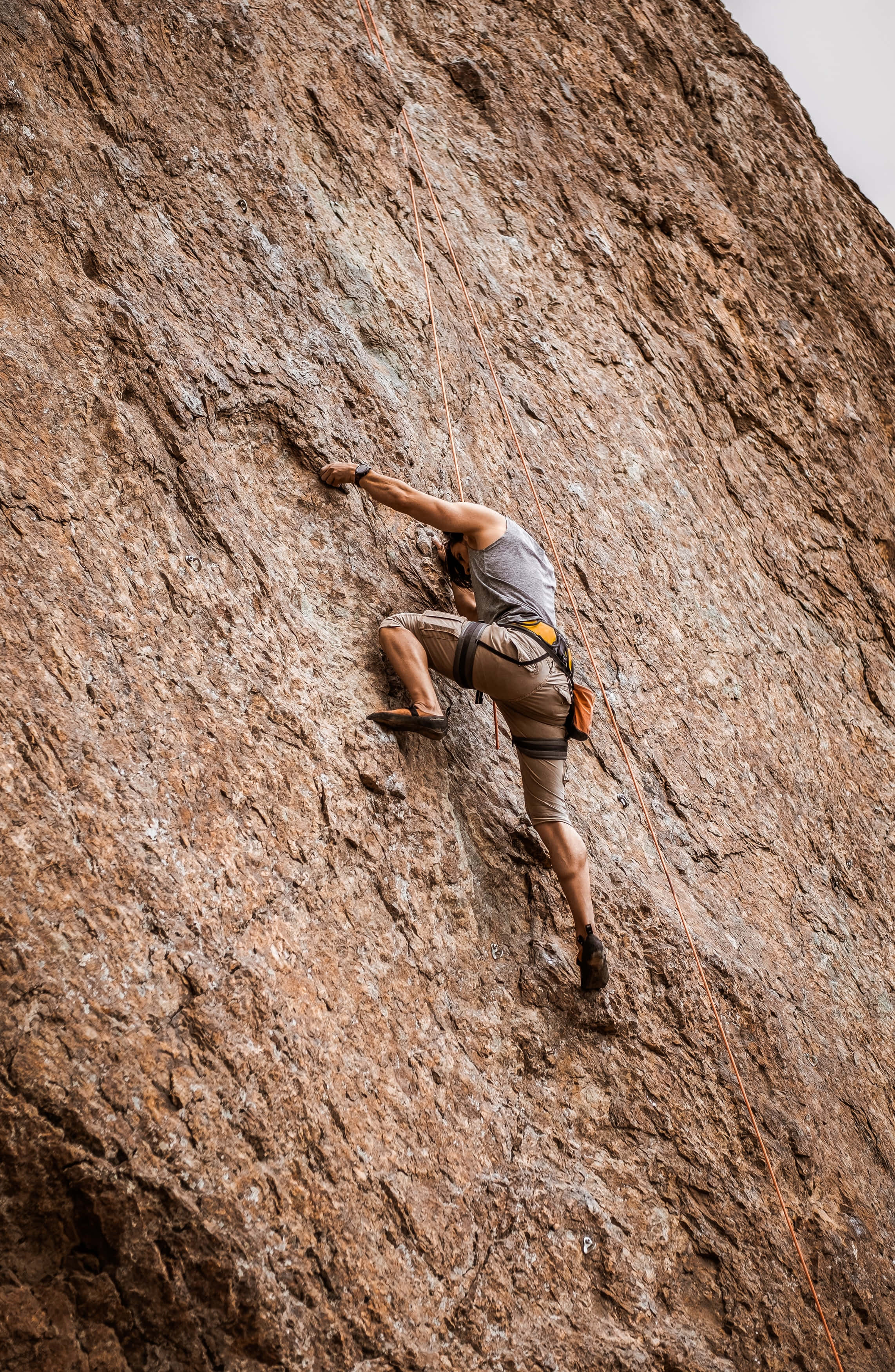 free climbing, rugged brown rock face, overcast sky, 2K Phone Wallpaper