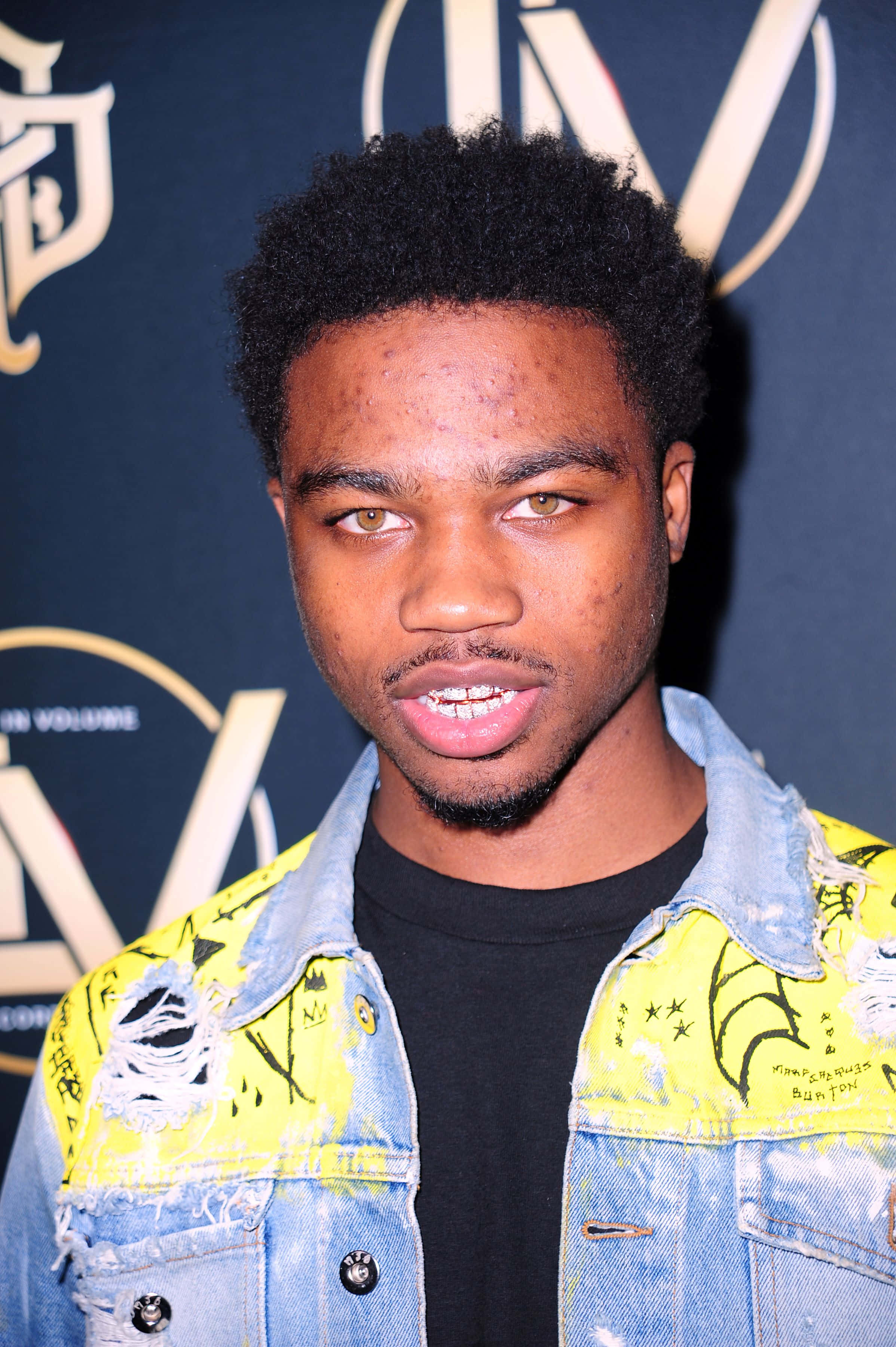 Roddy Ricch, bright yellow denim jacket, dark blue branded backdrop, 2K Phone Wallpaper