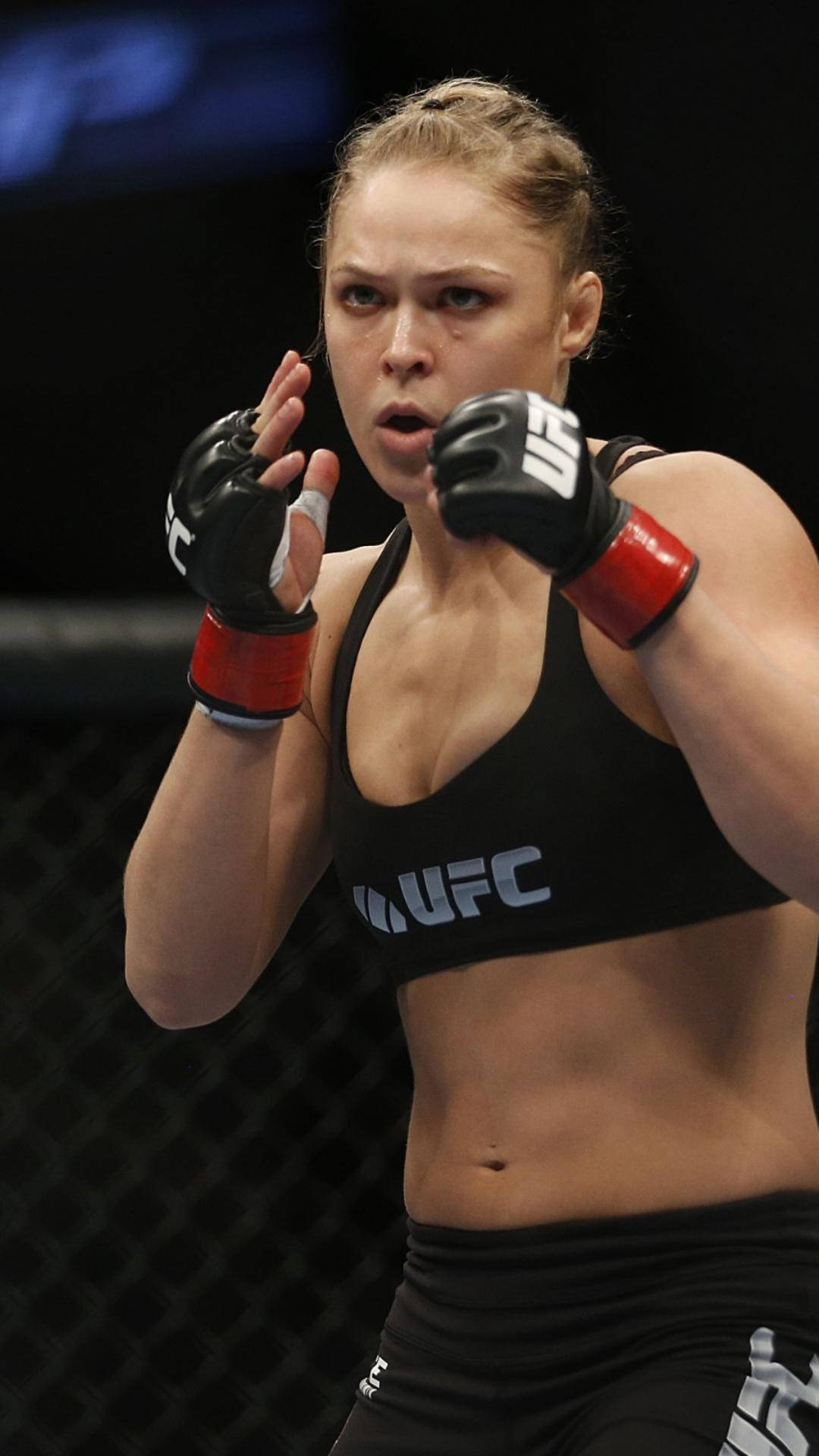 Ronda Rousey, black UFC gear, dimly lit octagon cage, Full HD Phone Wallpaper