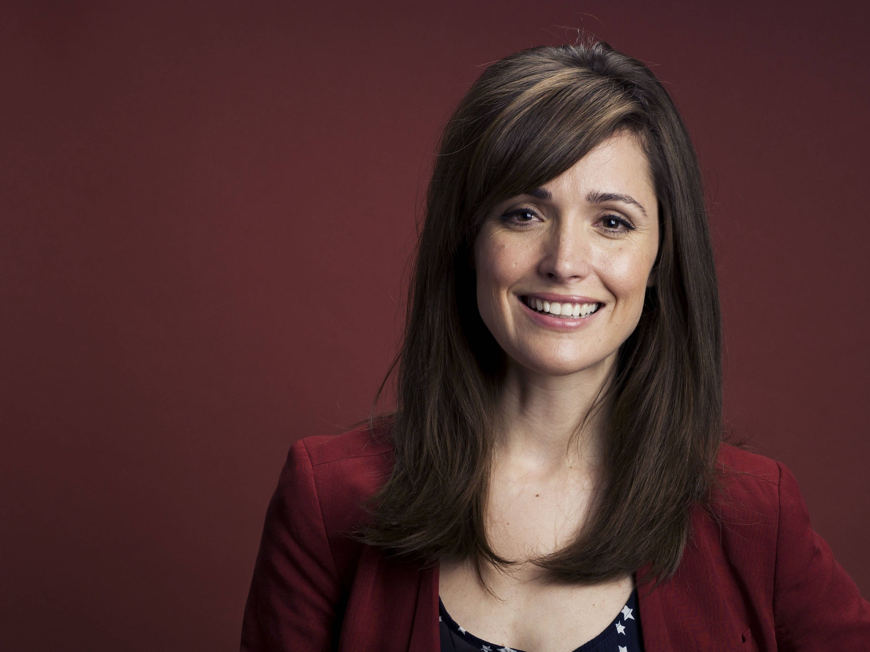 Rose Byrne, brown hair, deep red studio background, 2K Desktop Wallpaper