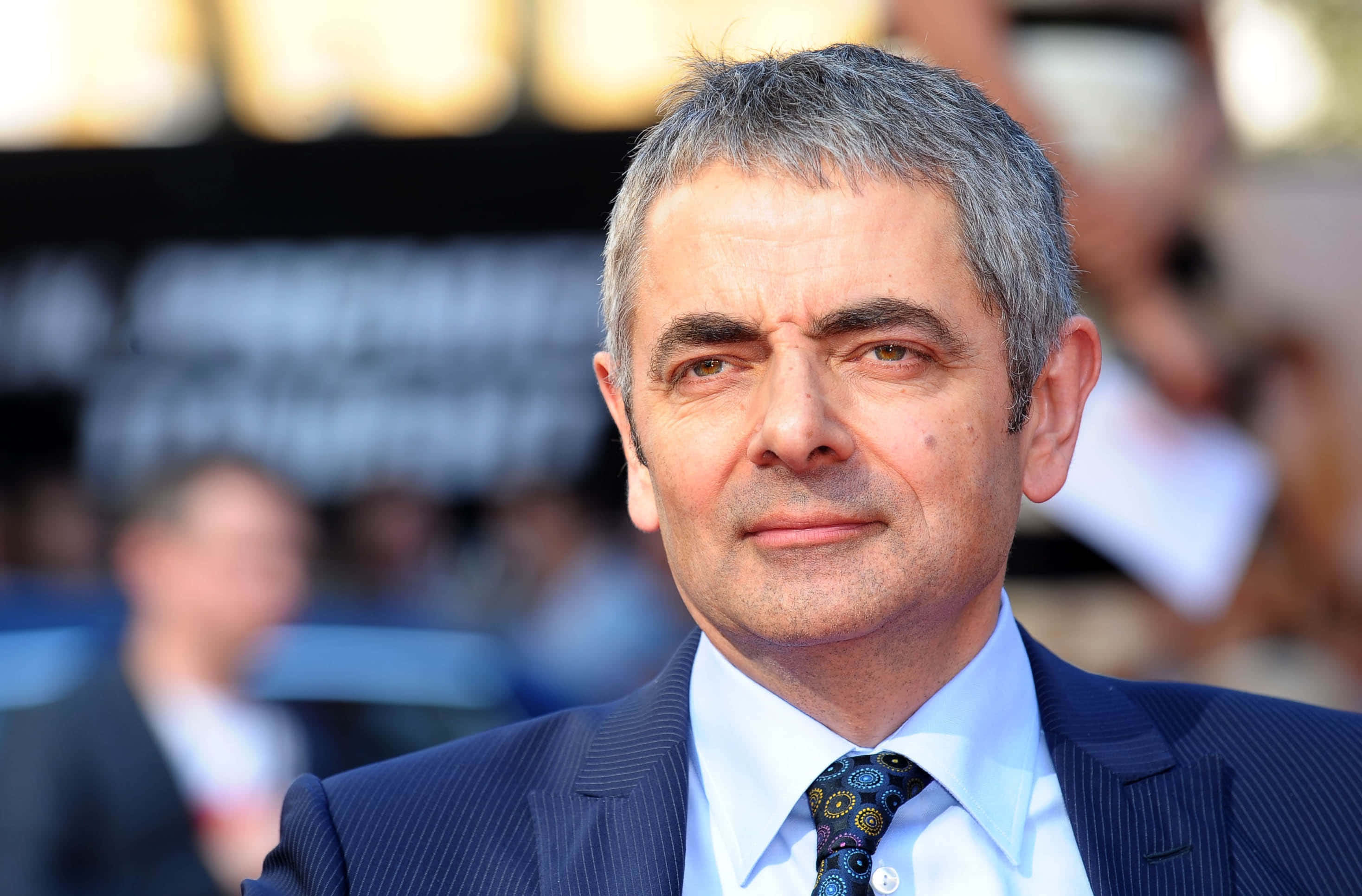 Rowan Atkinson, red carpet event, dark pinstripe suit, 2K Desktop Wallpaper