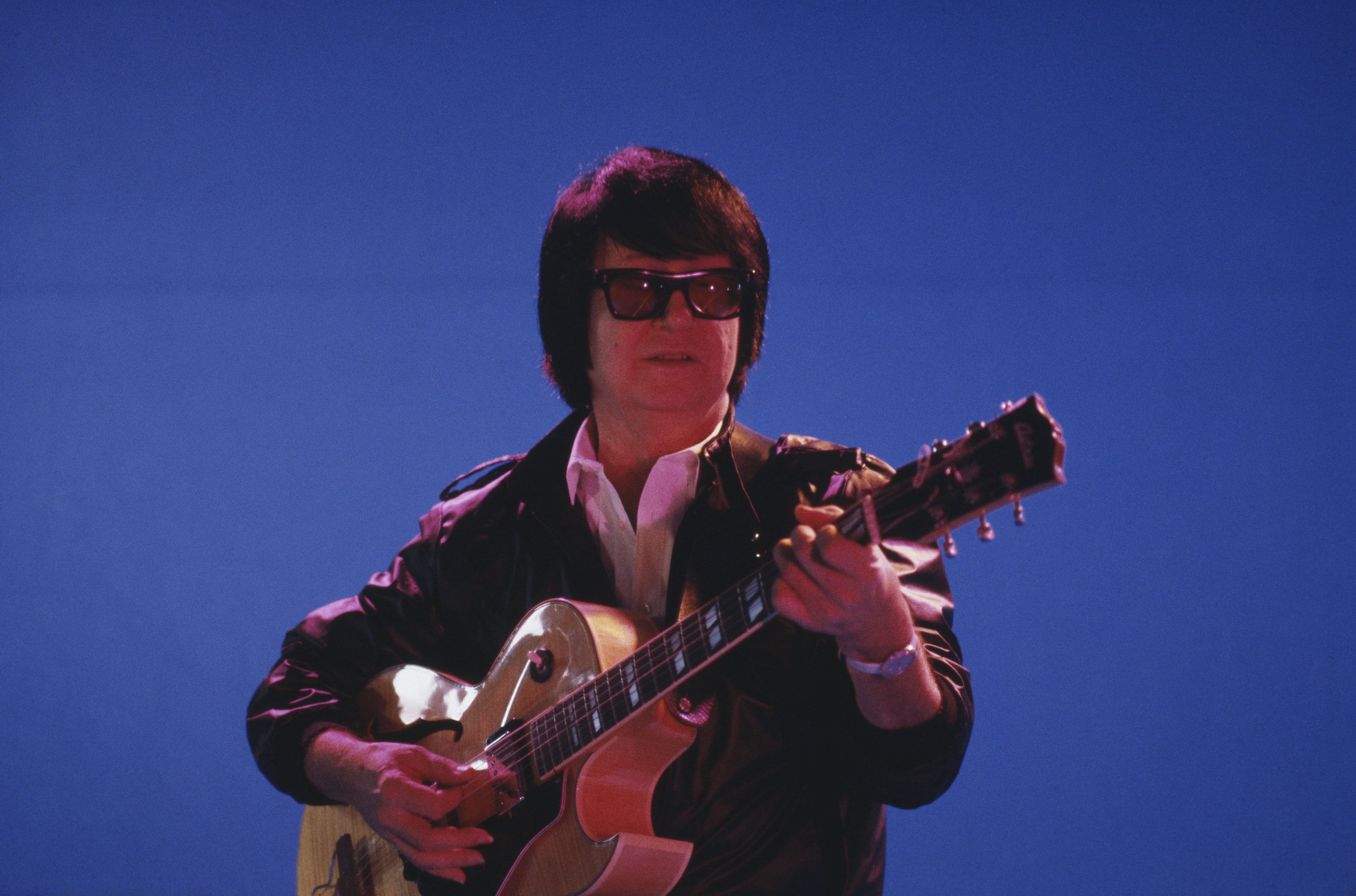 Roy Orbison, sunburst electric guitar, solid blue background, 5K Desktop Wallpaper