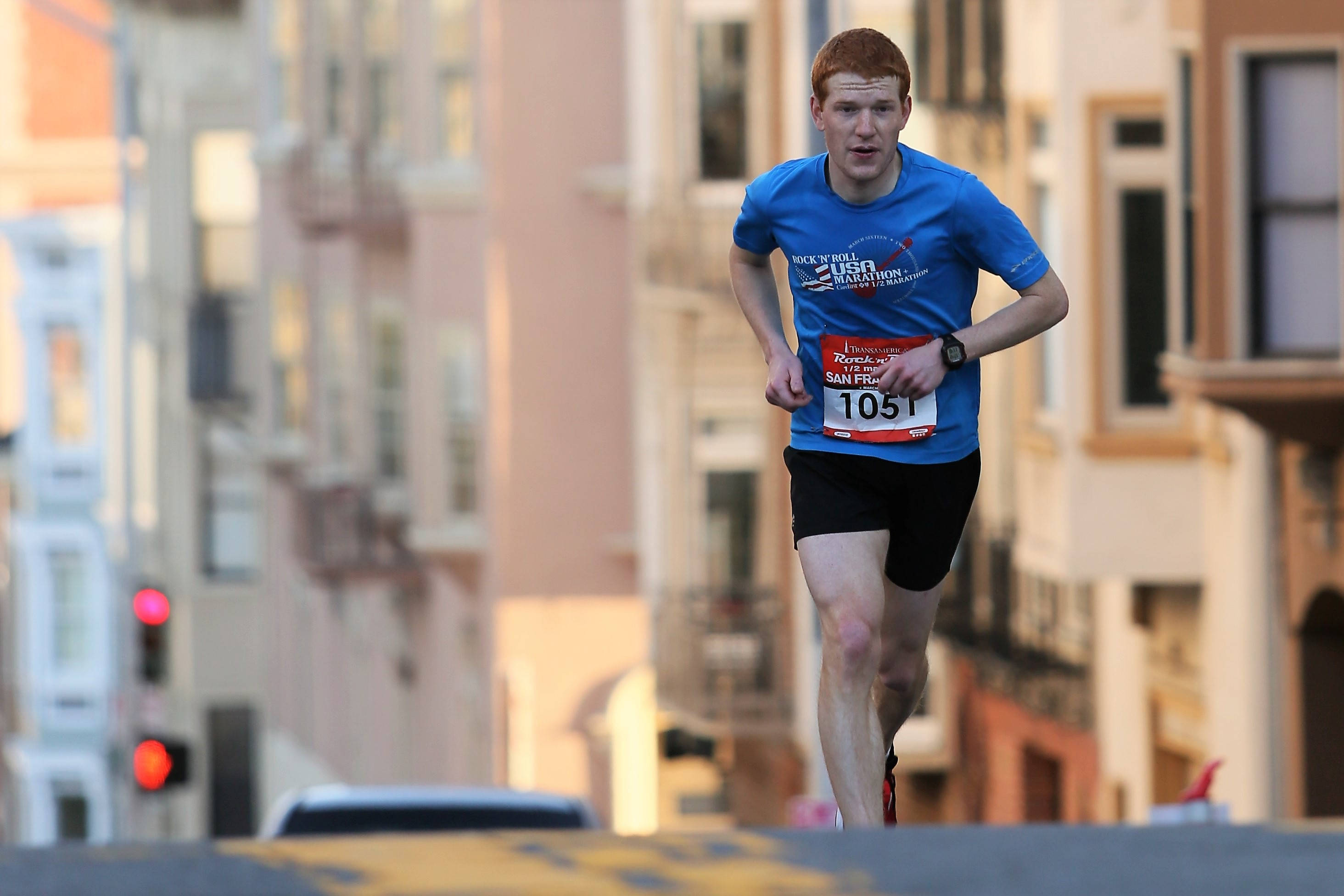 Runner, blue race shirt, sunlit urban street, 2K Desktop Wallpaper