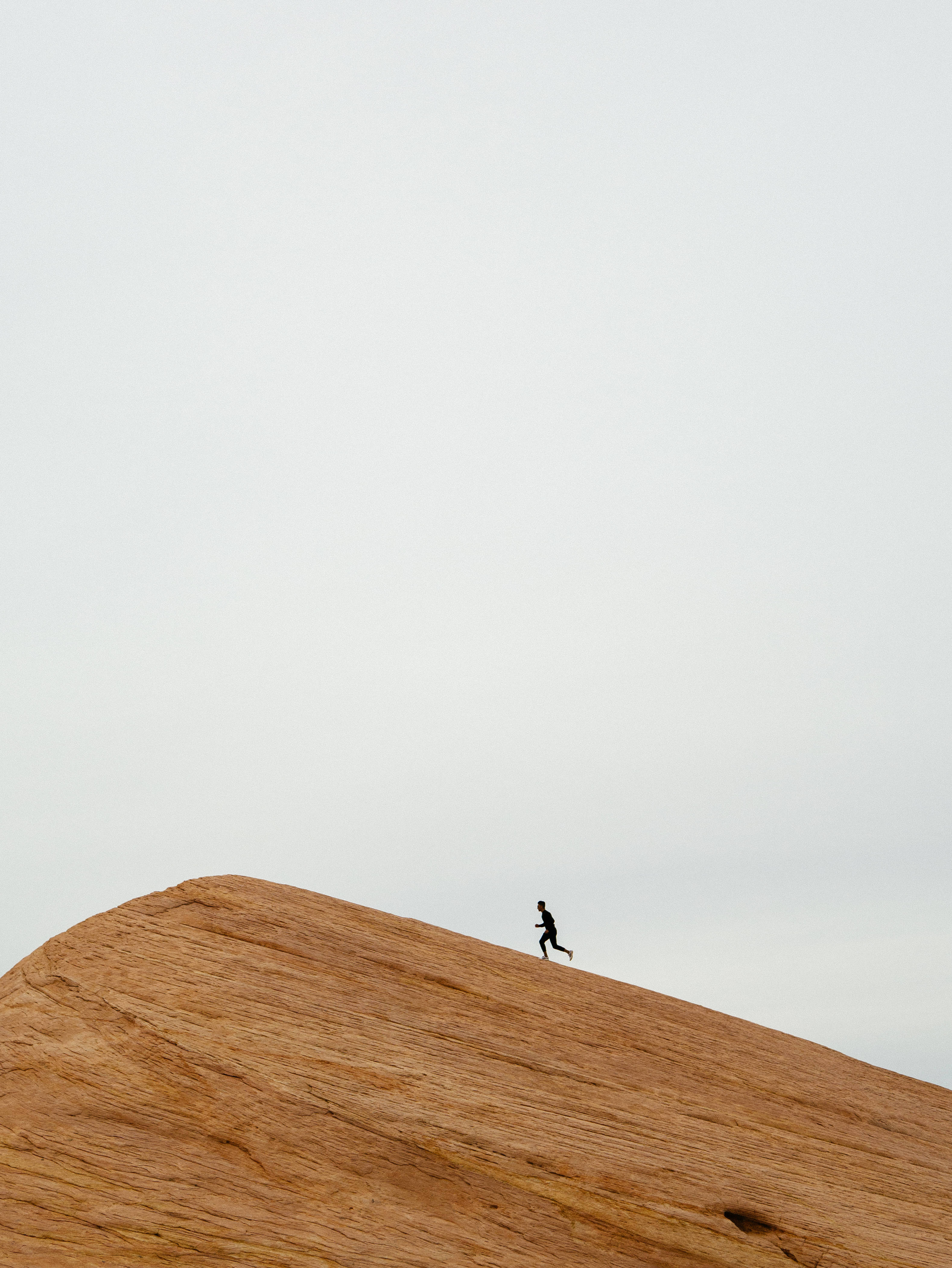 Inspirational Running Man, sunlit ridge, massive orange rock formation, 4K Phone Wallpaper
