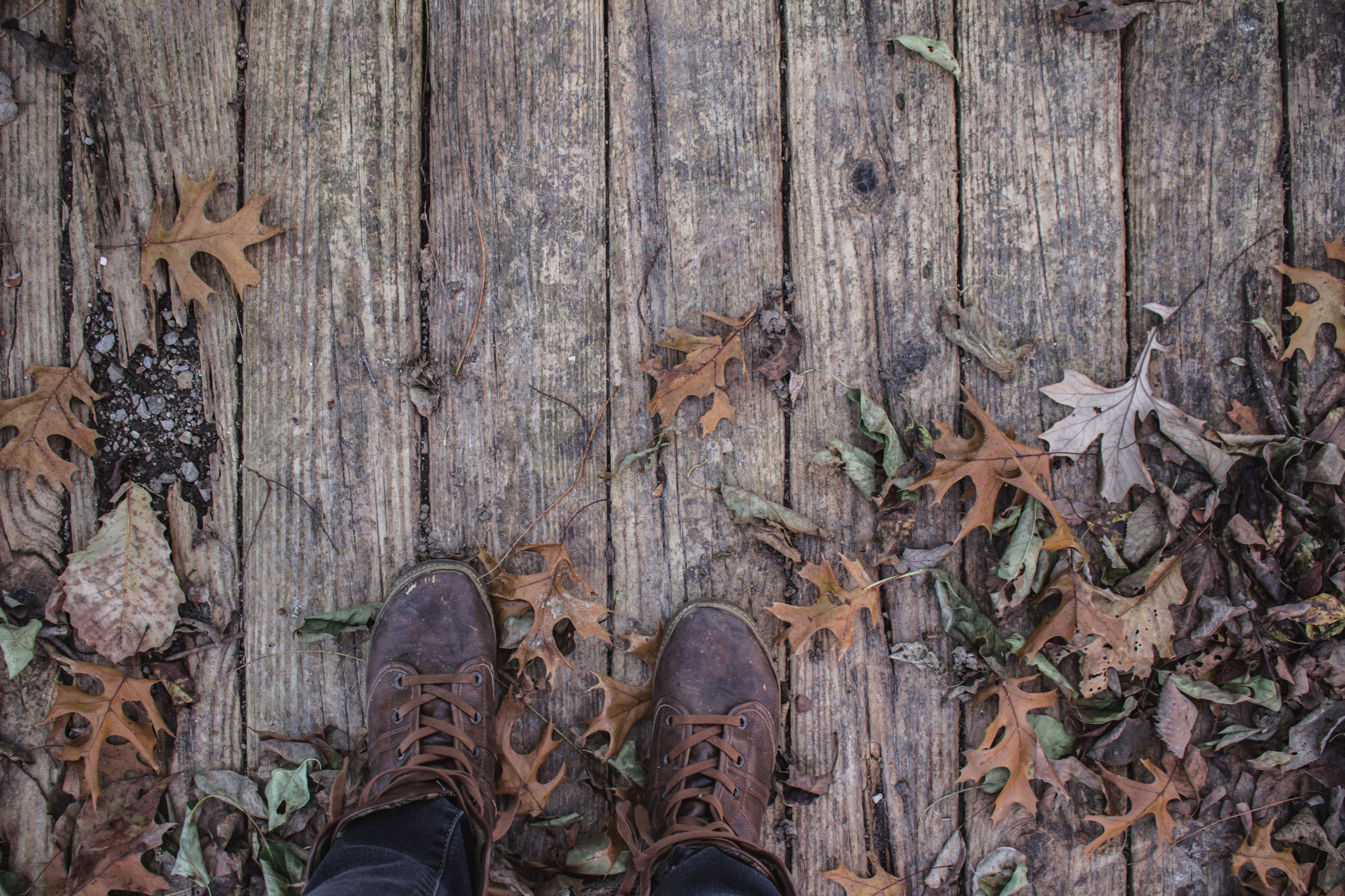 brown boots, weathered wooden deck, dry autumn leaves, 5K Desktop Wallpaper