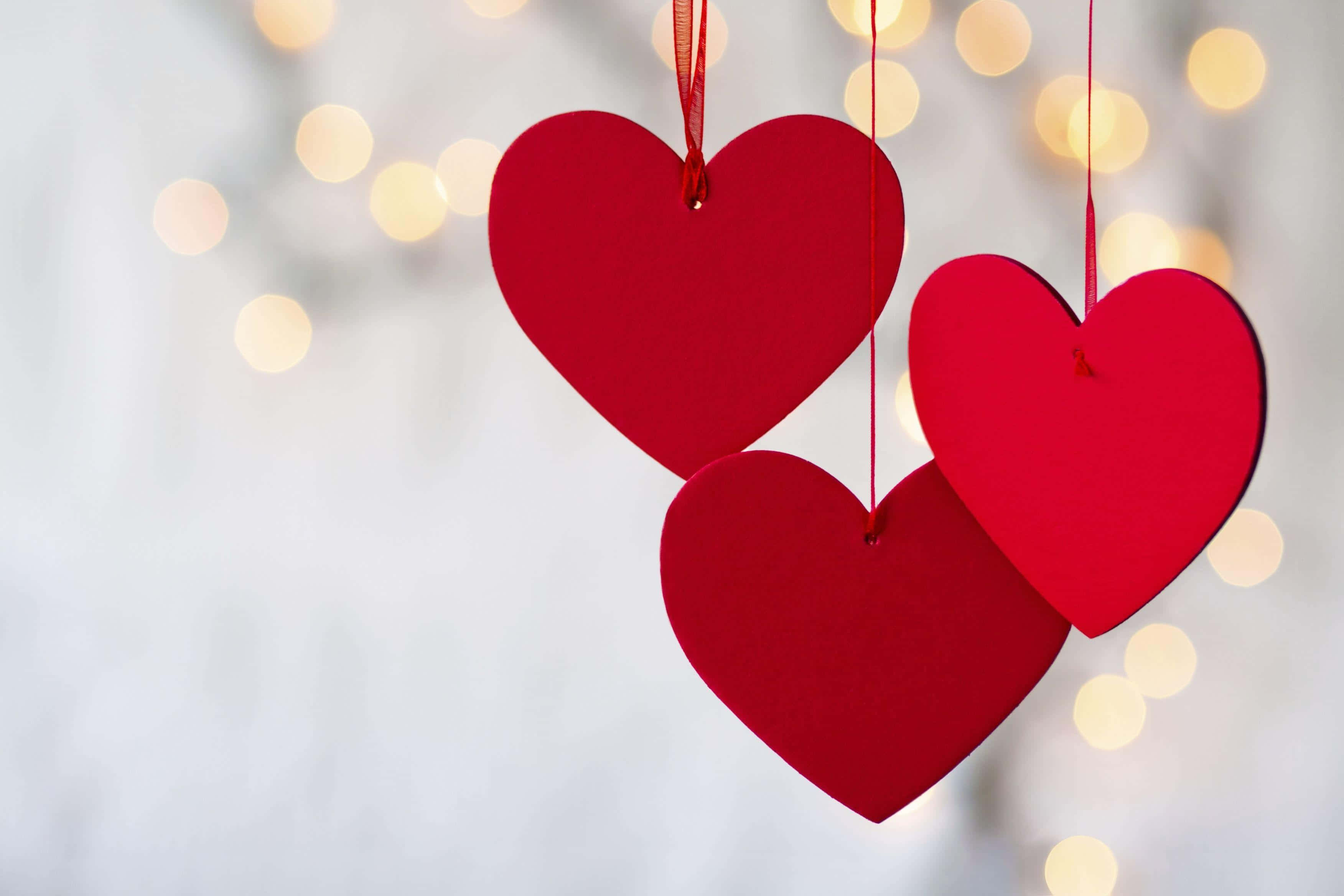three red hearts, strings, glowing golden bokeh lights, 2K Desktop Wallpaper
