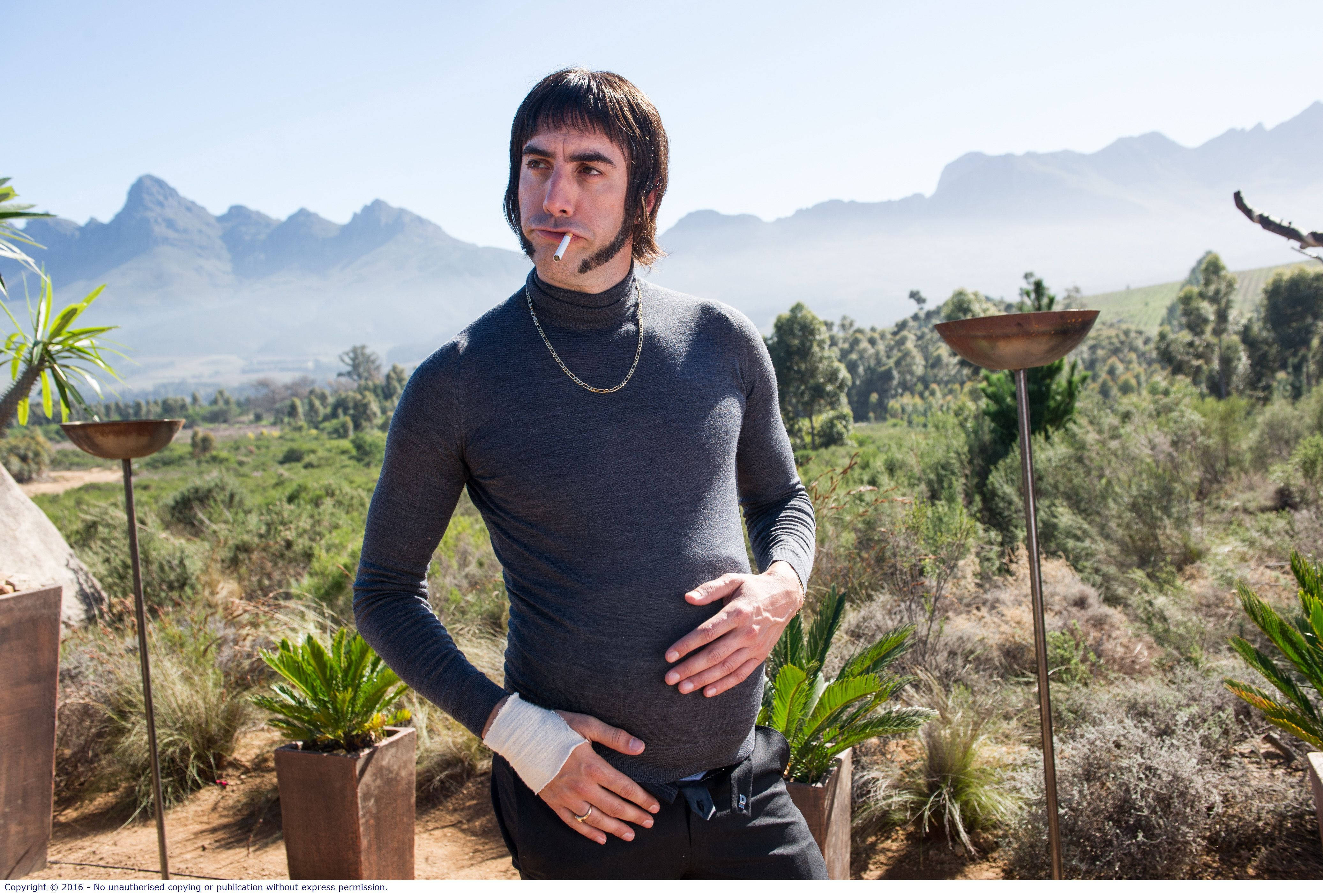 Caption: Sacha Baron Cohen transforming into his Norman Butcher Character, 4K Desktop Wallpaper