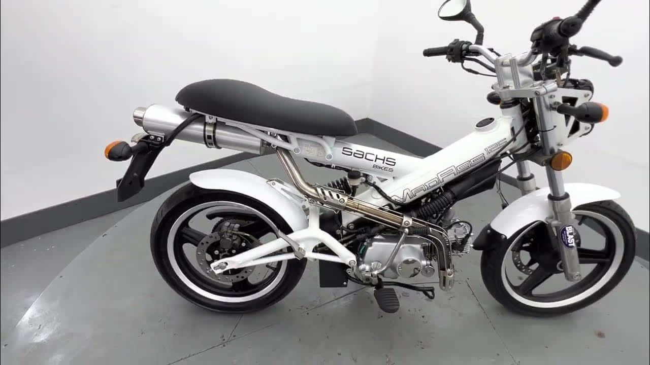 A sleek white Sachs moped with chrome accents and black seat stands in a clean indoor garage., HD Desktop Wallpaper