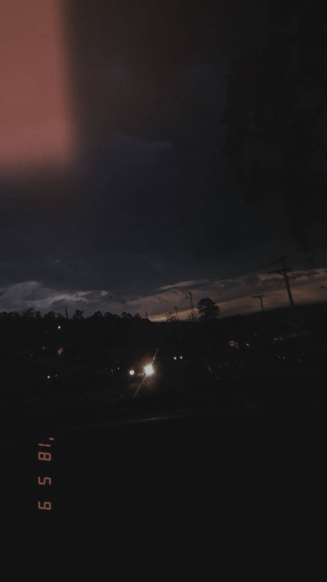 A dark urban twilight scene with distant streetlights glowing against a cloudy sky and silhouetted trees., Full HD Phone Wallpaper