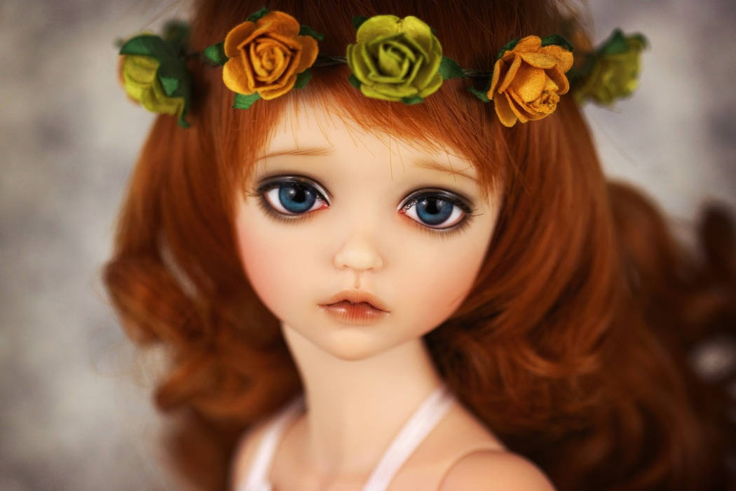 A close-up of a doll with large blue eyes and red hair adorned with a yellow and green rose crown., SD Desktop Wallpaper