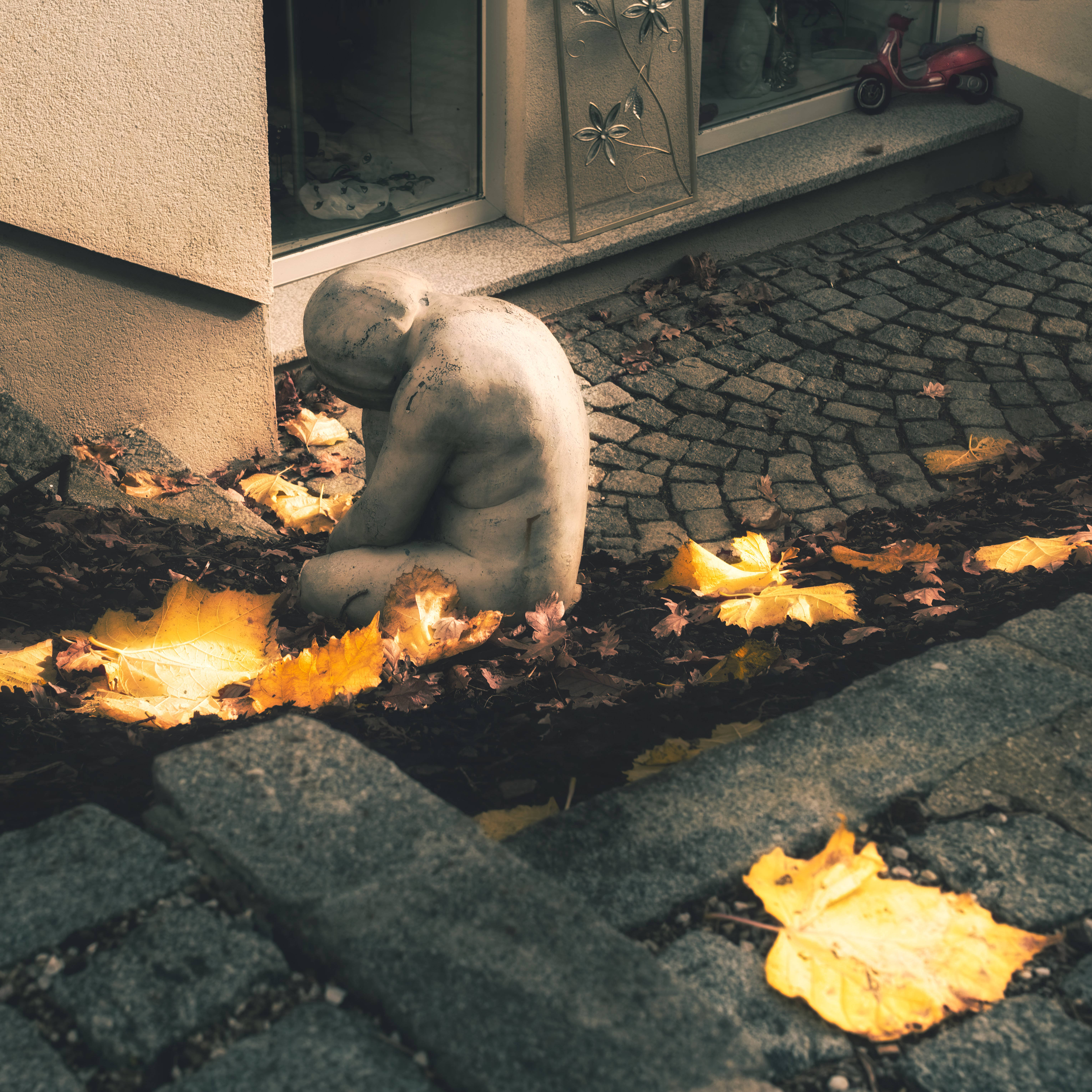 crouching child, weathered stone statue, golden leaves, 5K Desktop Wallpaper