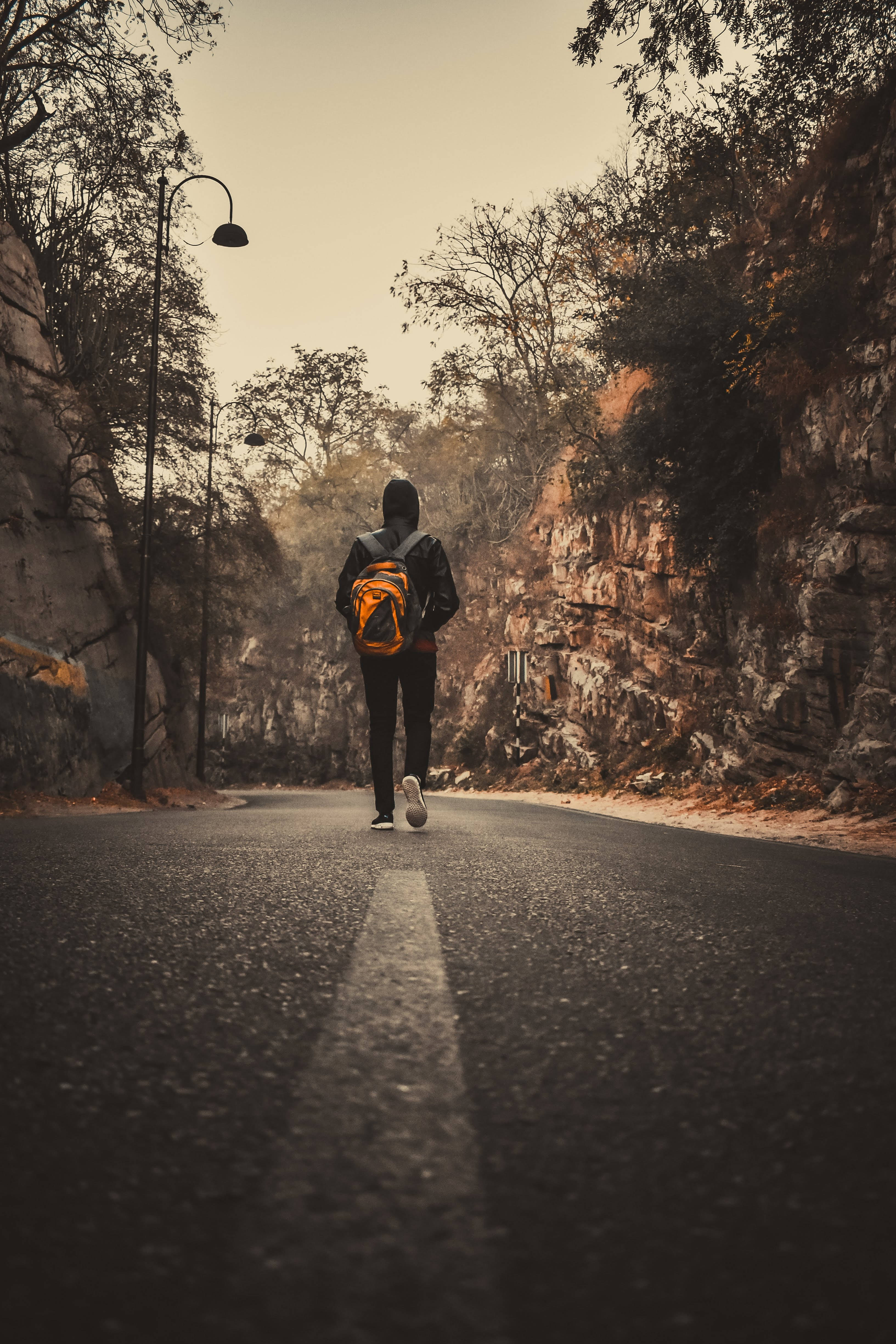 orange backpack, winding mountain road, rocky cliffs, 4K Phone Wallpaper