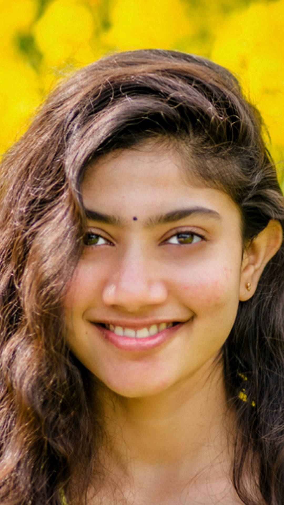 Sai Pallavi, wavy brown hair, vibrant yellow floral backdrop, Full HD Phone Wallpaper